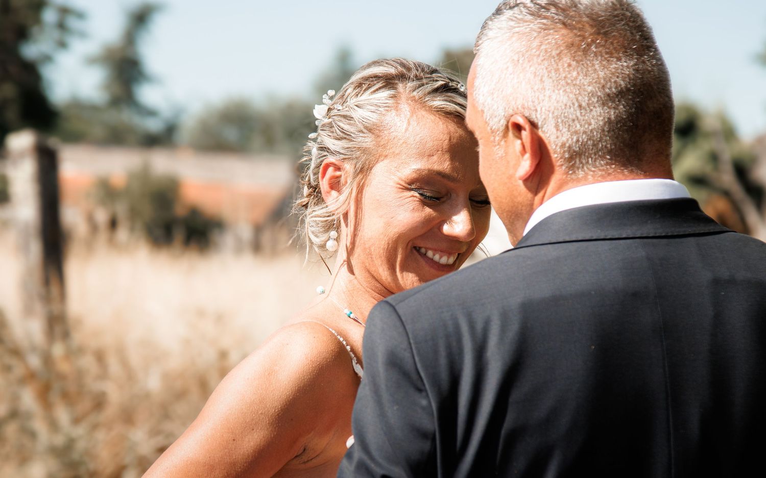 A tender moment between newlyweds captured in warm sunlight outdoors.
