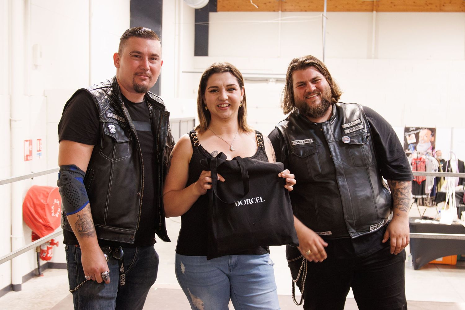 Group photo showing people in motorcycle vests posing together indoors.