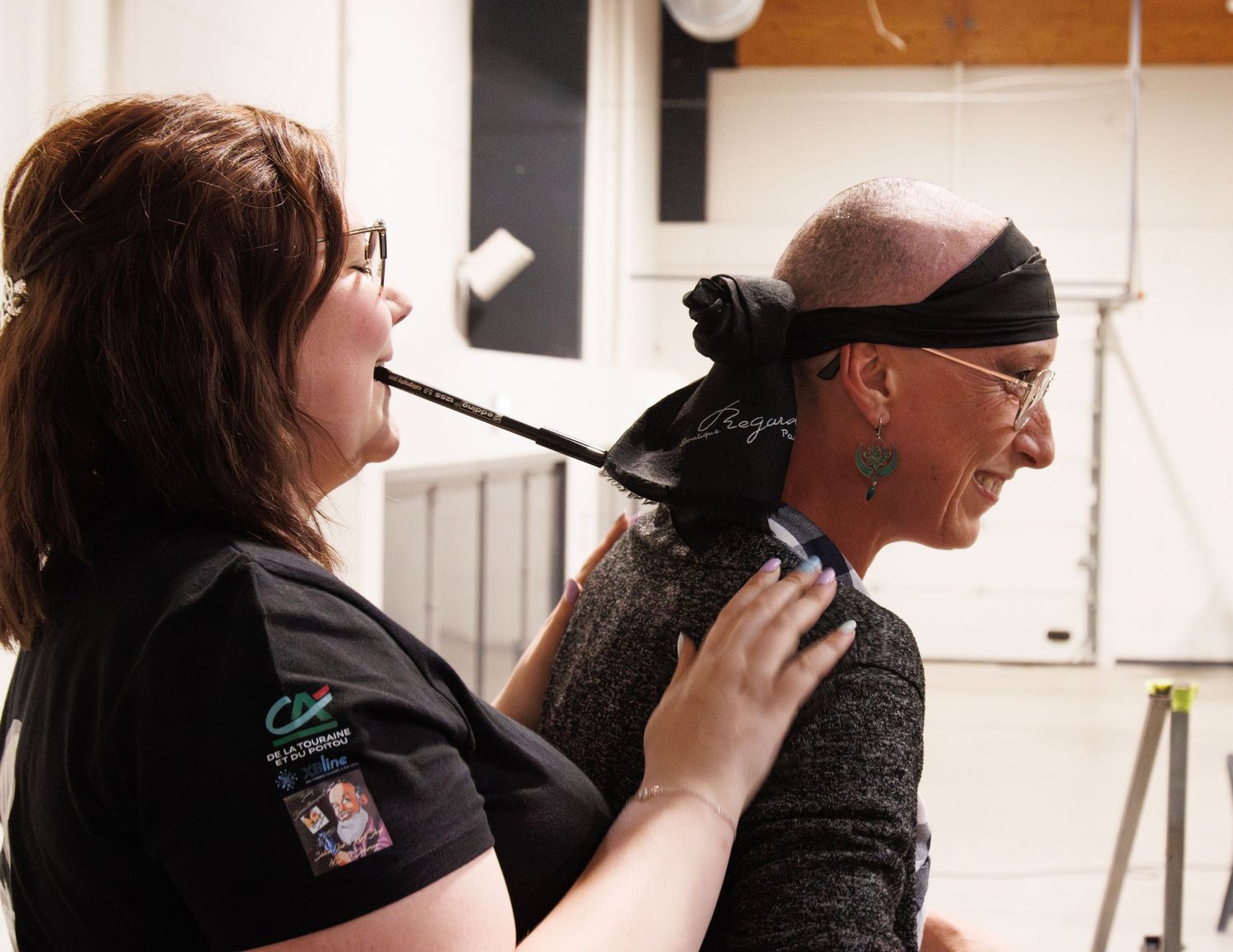 Two people preparing for arm wrestling competition as one gets a black bandana tied around their head.
