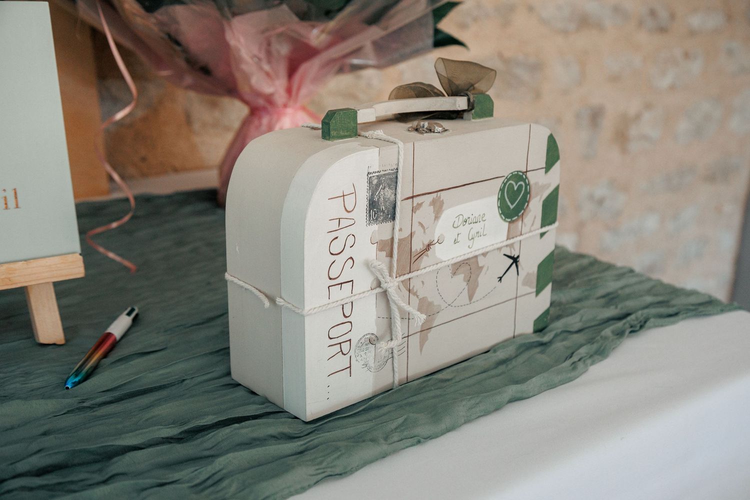 Decorative travel-themed suitcase wedding card box with passport design on marble table.