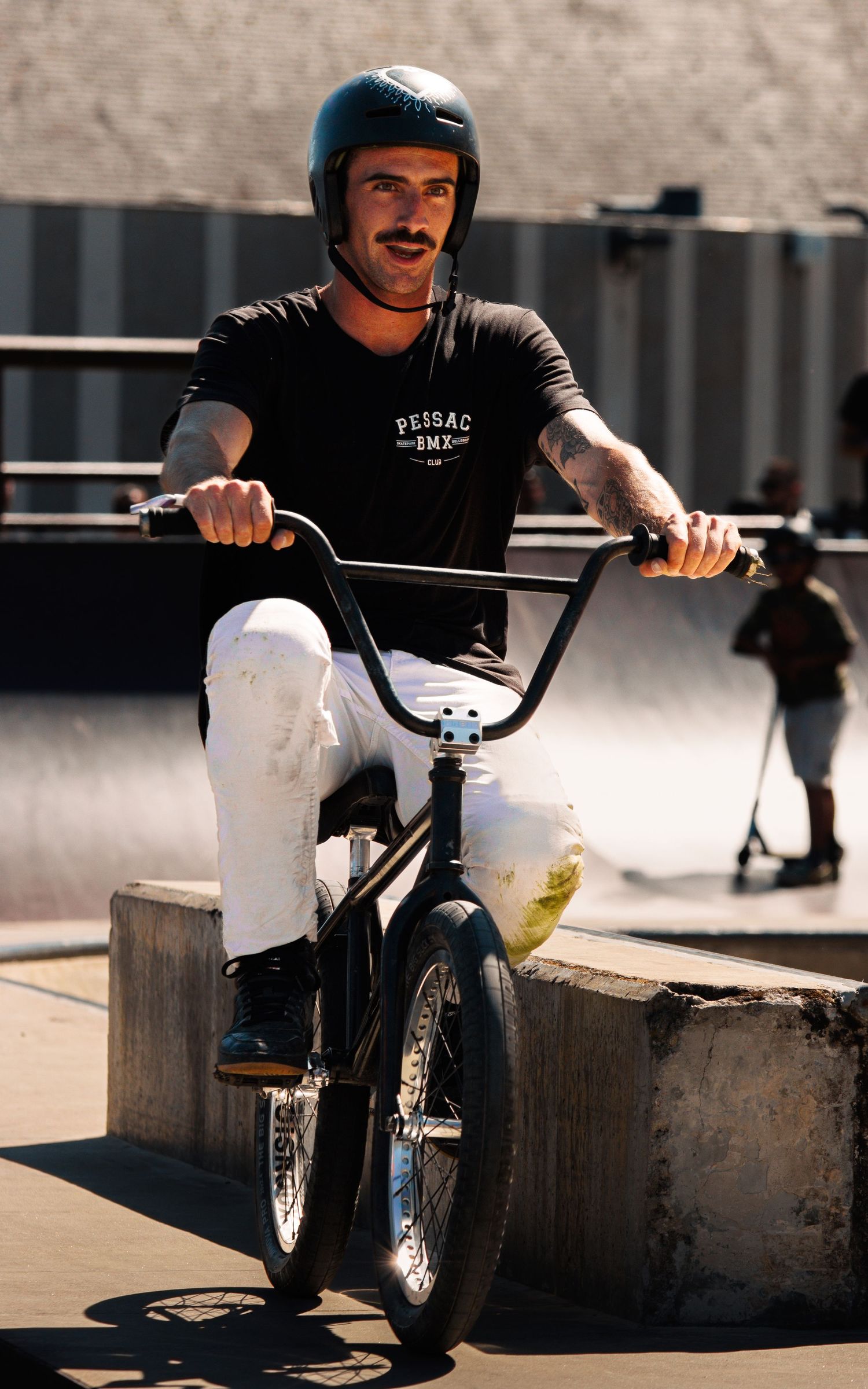 BMX rider performs tricks on concrete ledge in urban setting during sunny day.