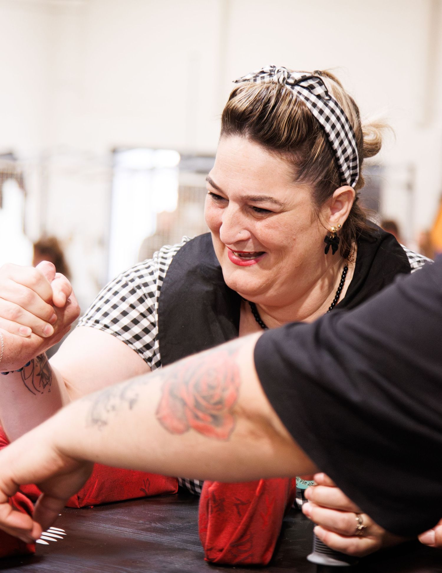 Woman in checkered headband smiling during an arm wrestling match.