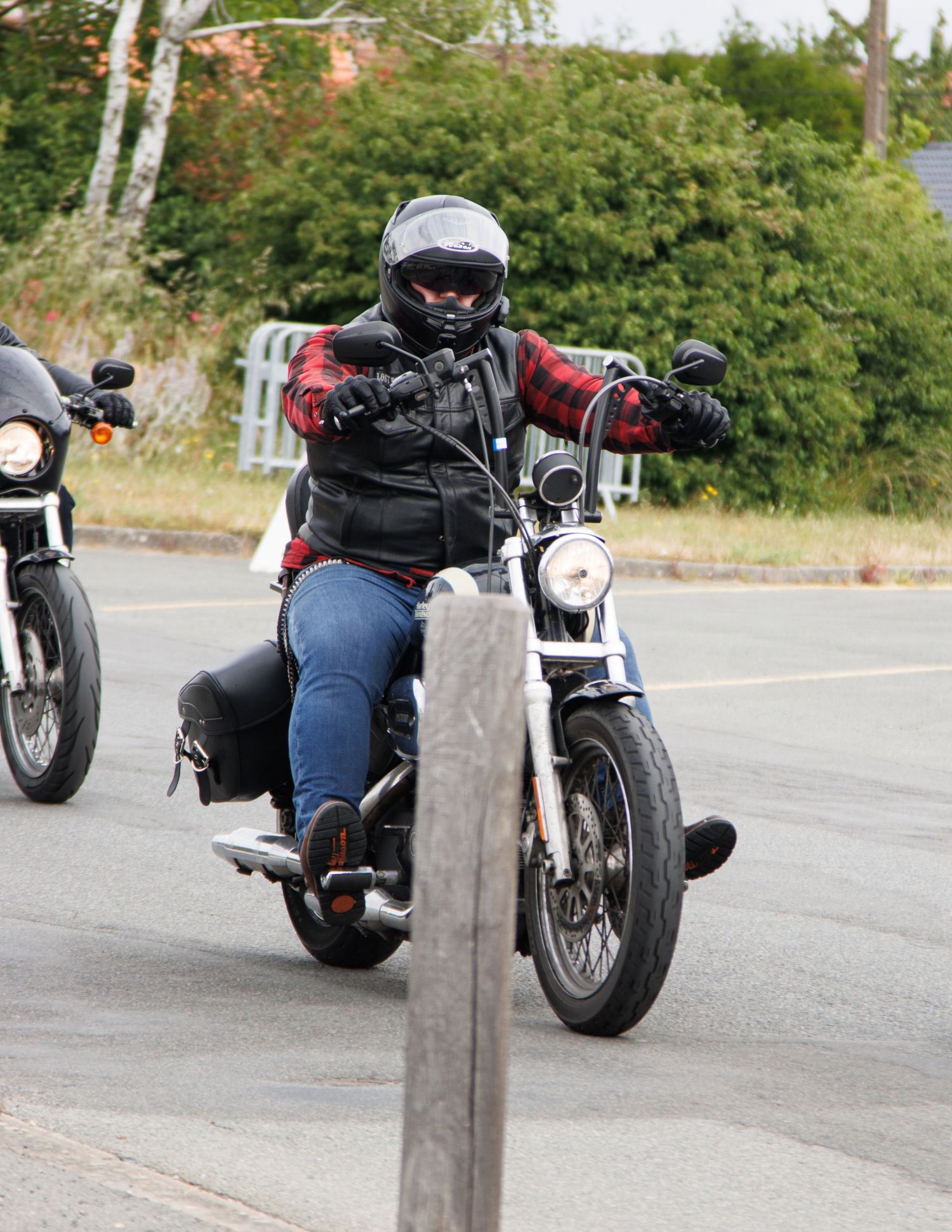 Motorcycle rider in protective gear cruising on a custom bike along a curved road.