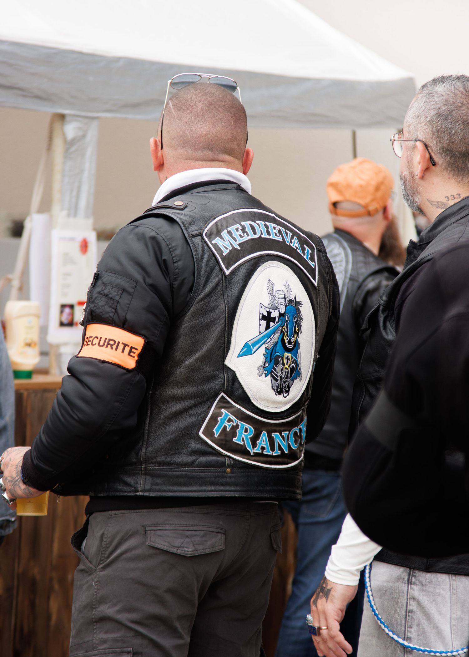 Motorcycle club vests with patches visible at an indoor gathering.