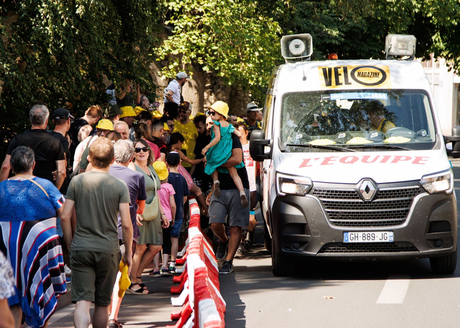 Crowd of spectators gathering around a Renault support vehicle during a cycling event.