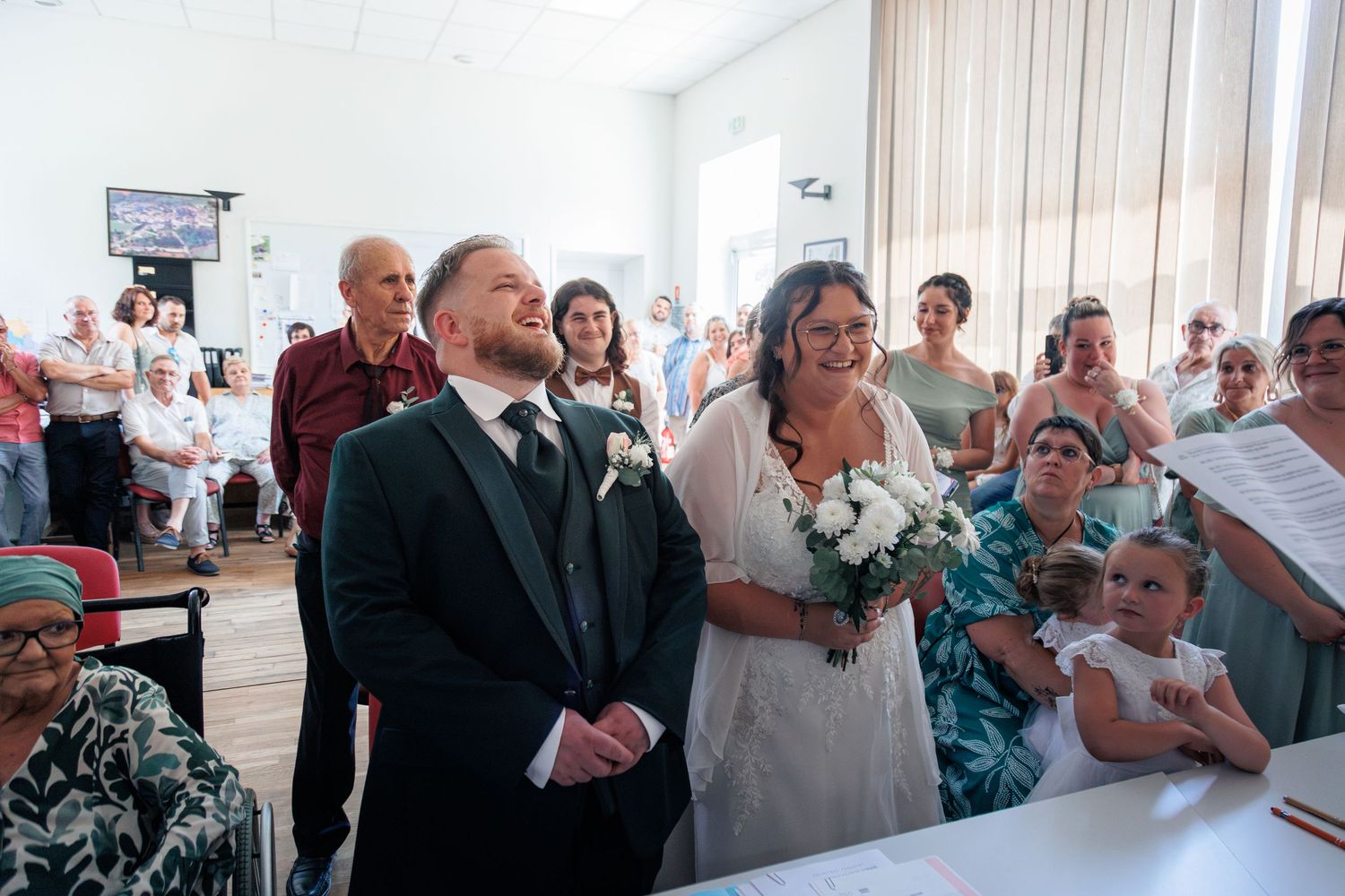 Bride and groom stand together smiling during their French civil wedding ceremony indoors.