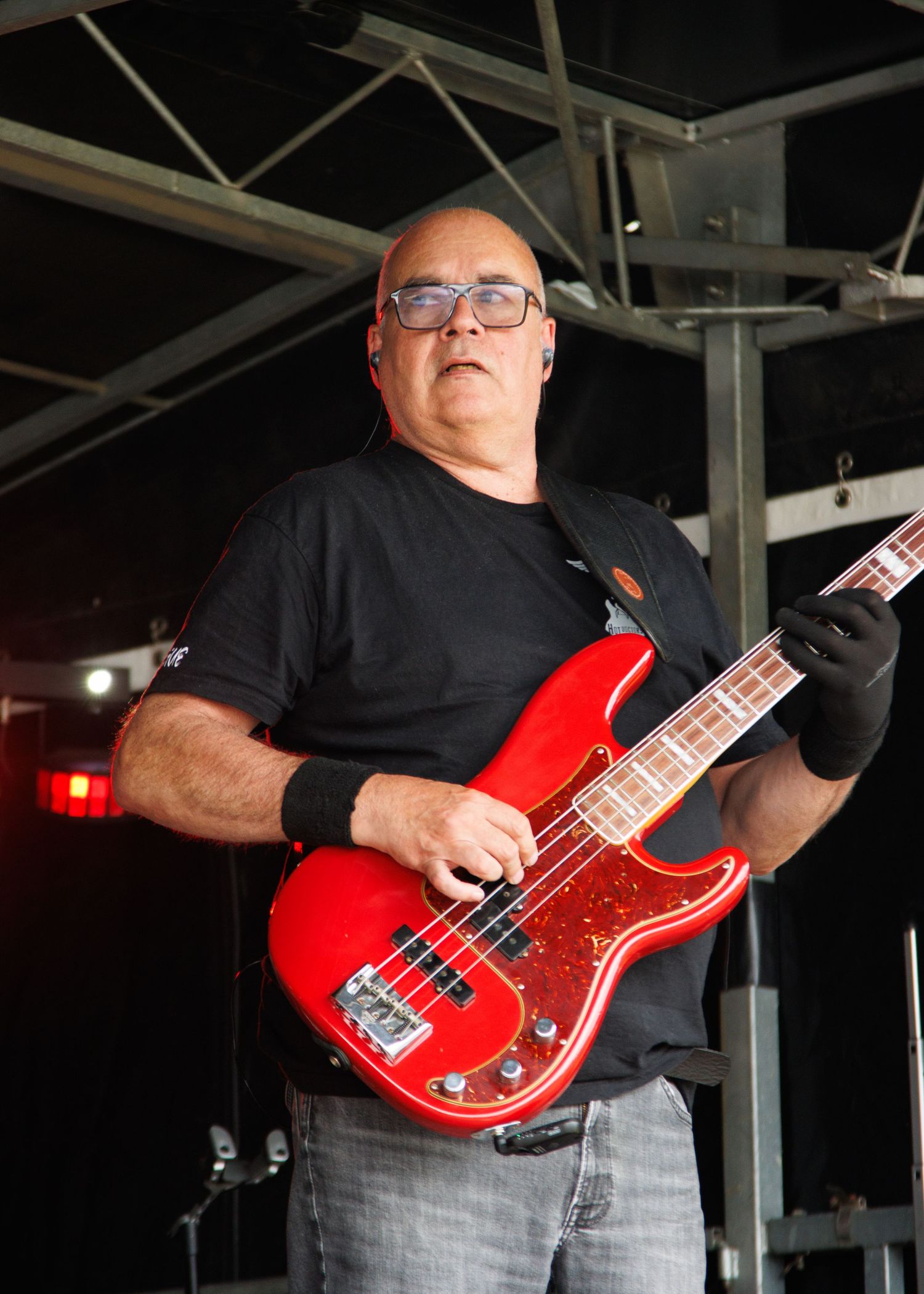 Musician playing a bright red bass guitar on stage during a performance.