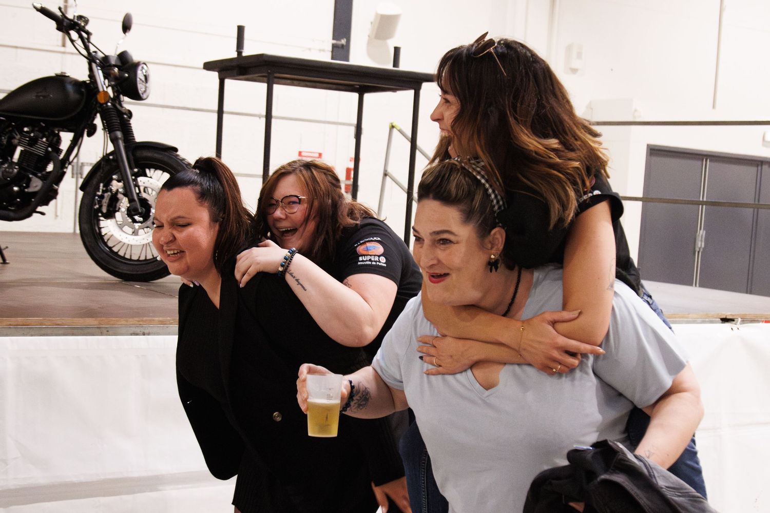 Friends sharing a playful moment together while posing near a motorcycle indoors.