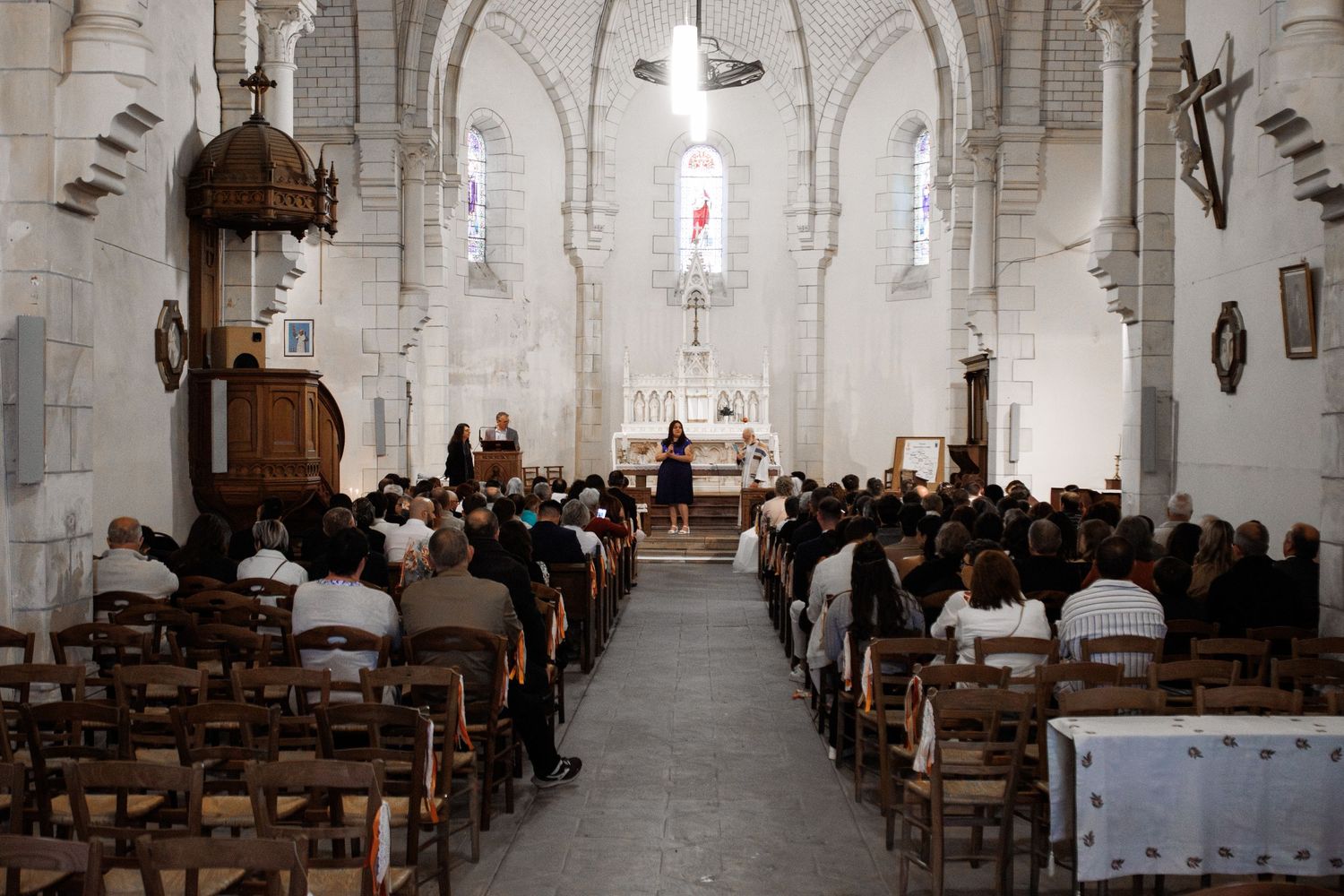 Congregation gathered inside a historic stone church with wooden pews during a religious ceremony.