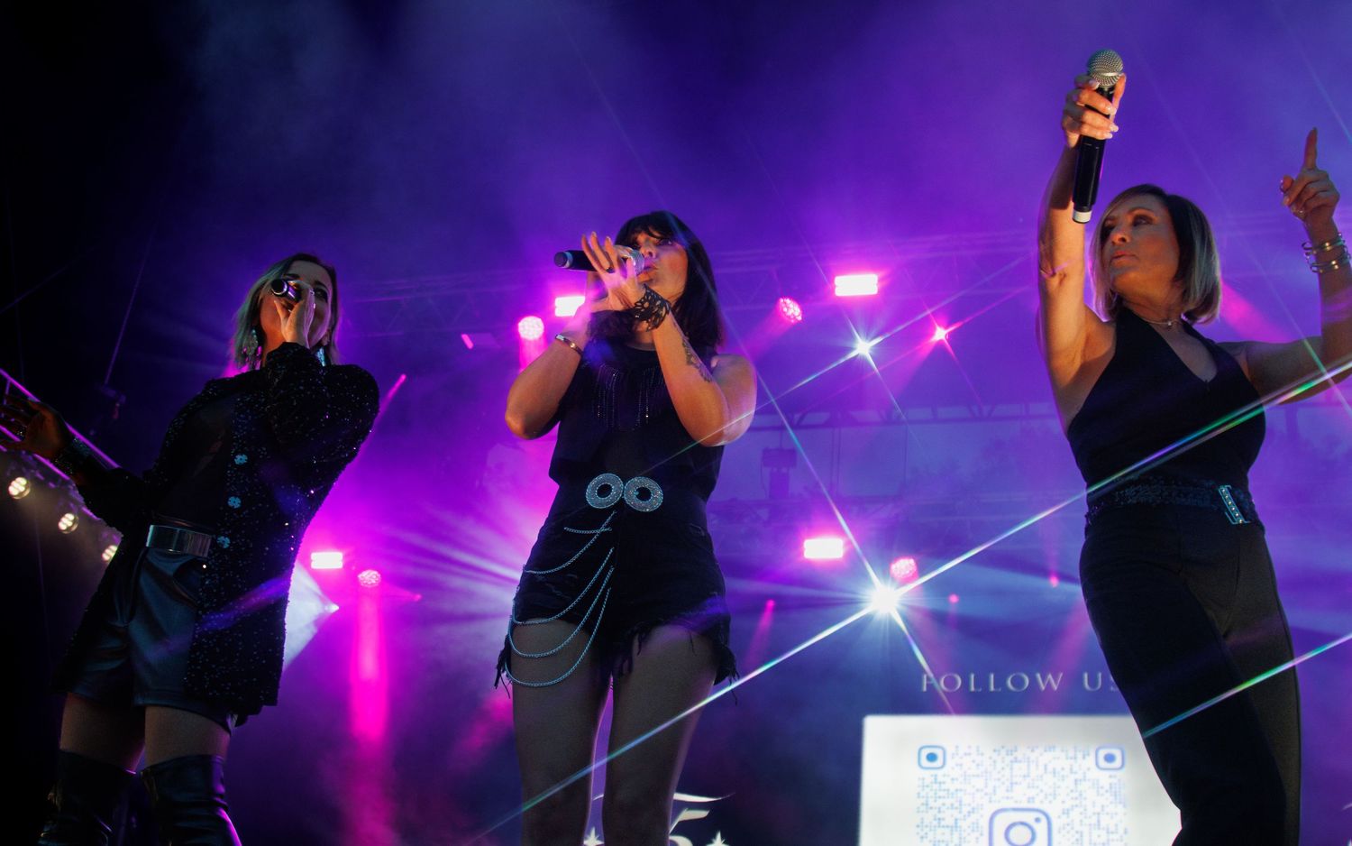 Concert performance with purple stage lighting and silhouetted figures captured in dynamic poses during live show.