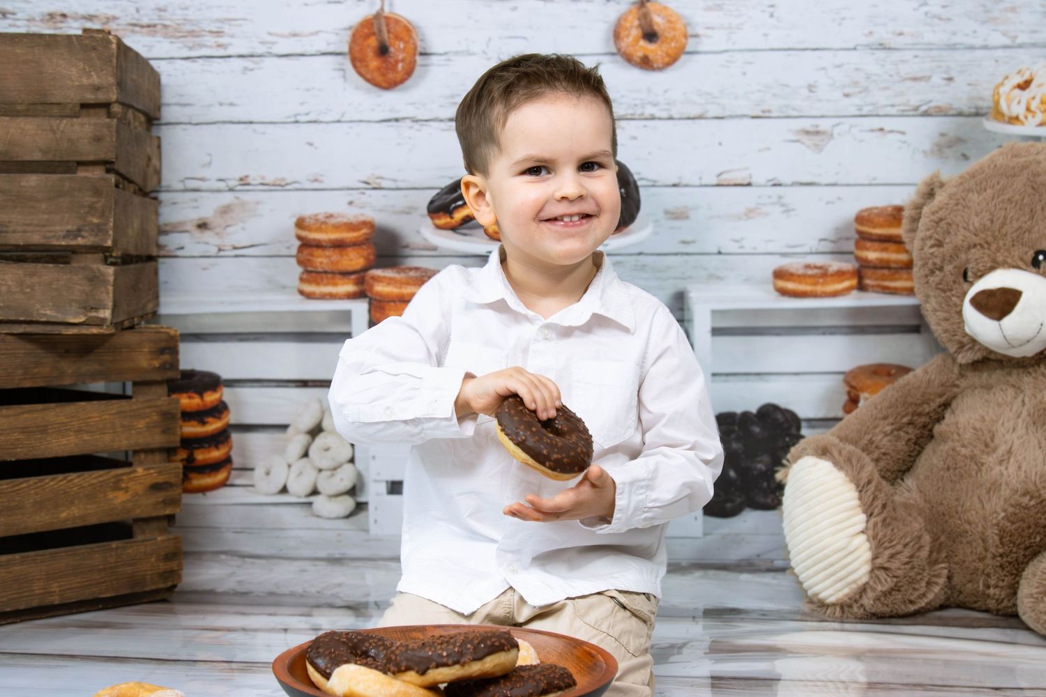 Child holding cookies near wooden crates and stuffed animals in rustic setting.