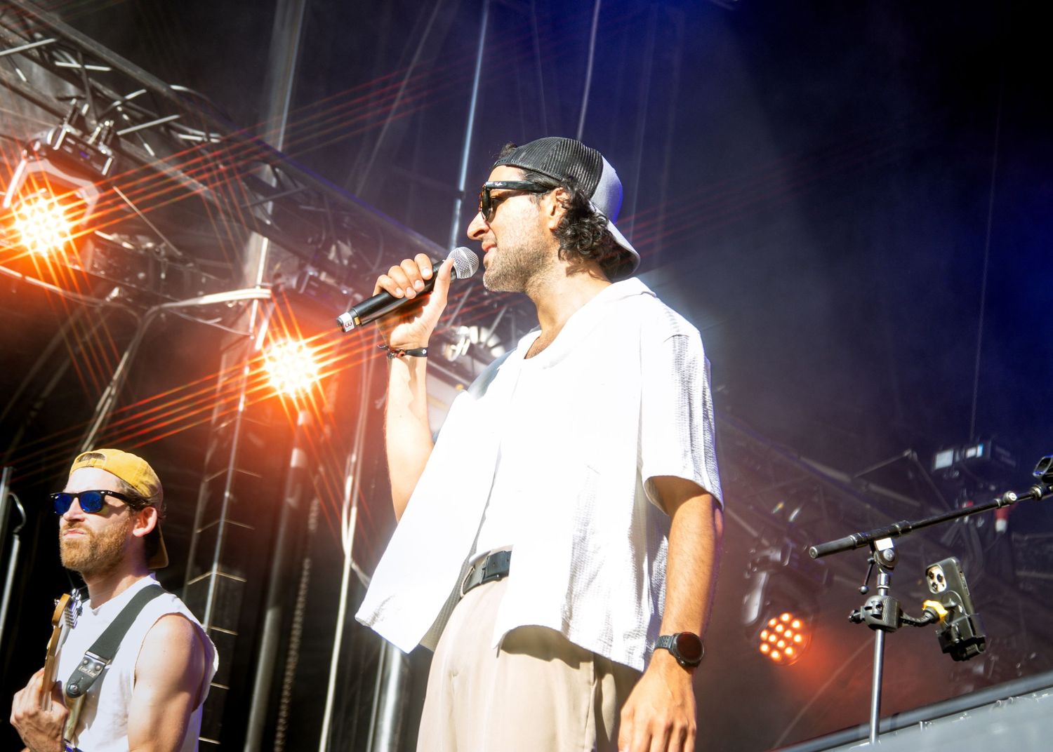 Musicians perform on stage under bright spotlights during a live concert performance.