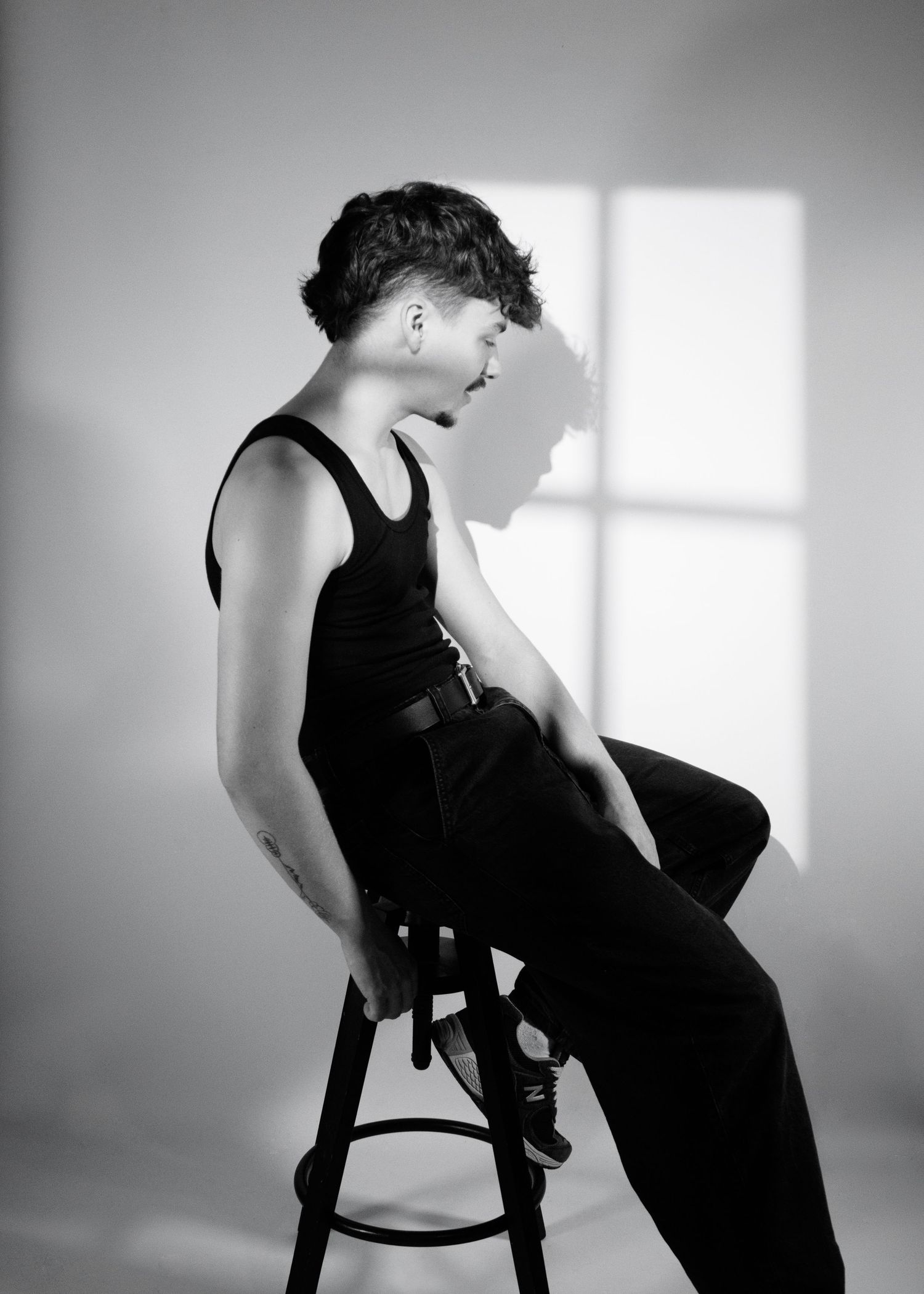 A black and white artistic sequence showing a figure in dark clothing seated on a chair against a light background.