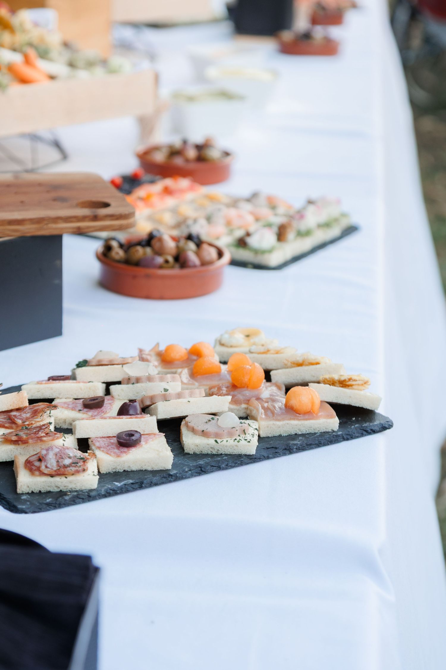 Elegant wedding reception buffet table with assorted appetizers and canapes on slate boards.
