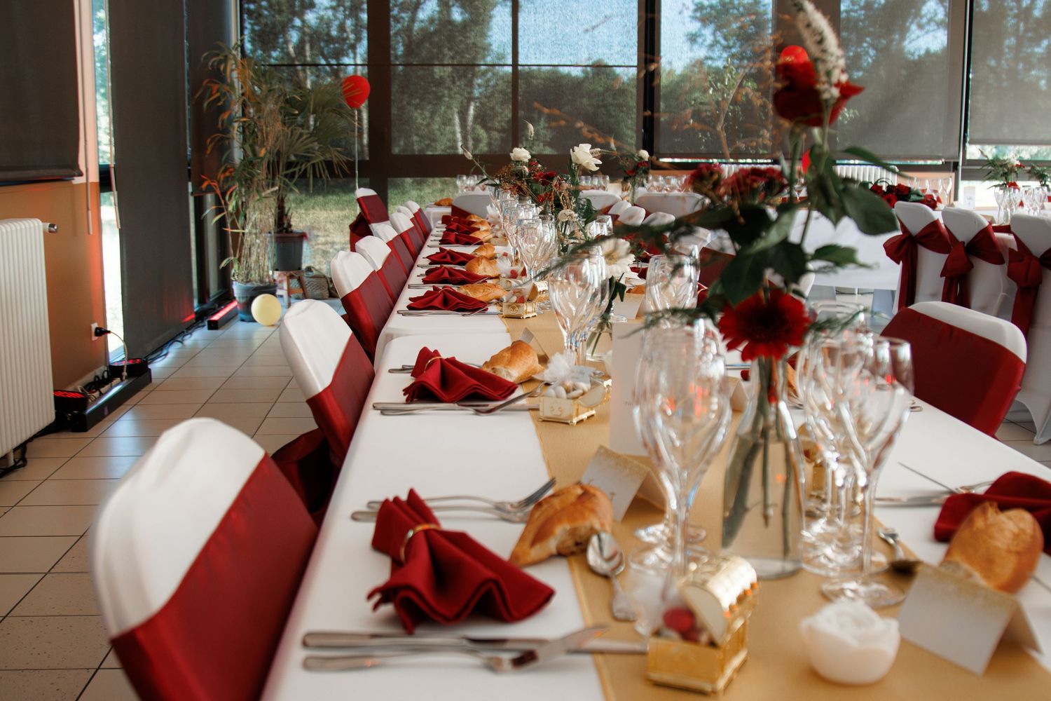 Elegant wedding reception table set with red napkins, roses, and crystal glassware.