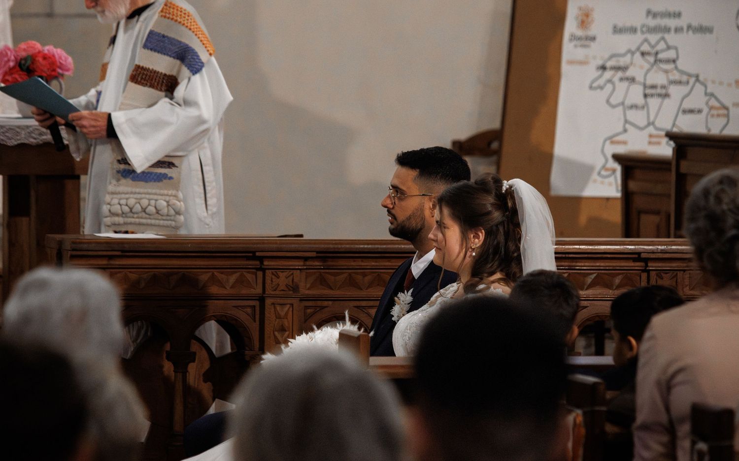 Couple exchanging wedding vows at a church altar during a religious ceremony with a priest officiating.