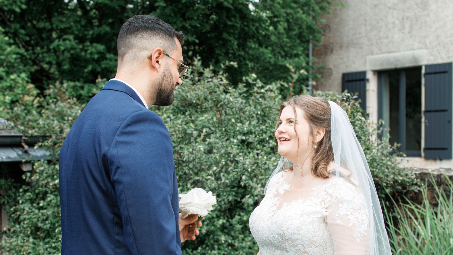 Bride and groom sharing a romantic moment outdoors on their wedding day, bride holding a white bouquet.