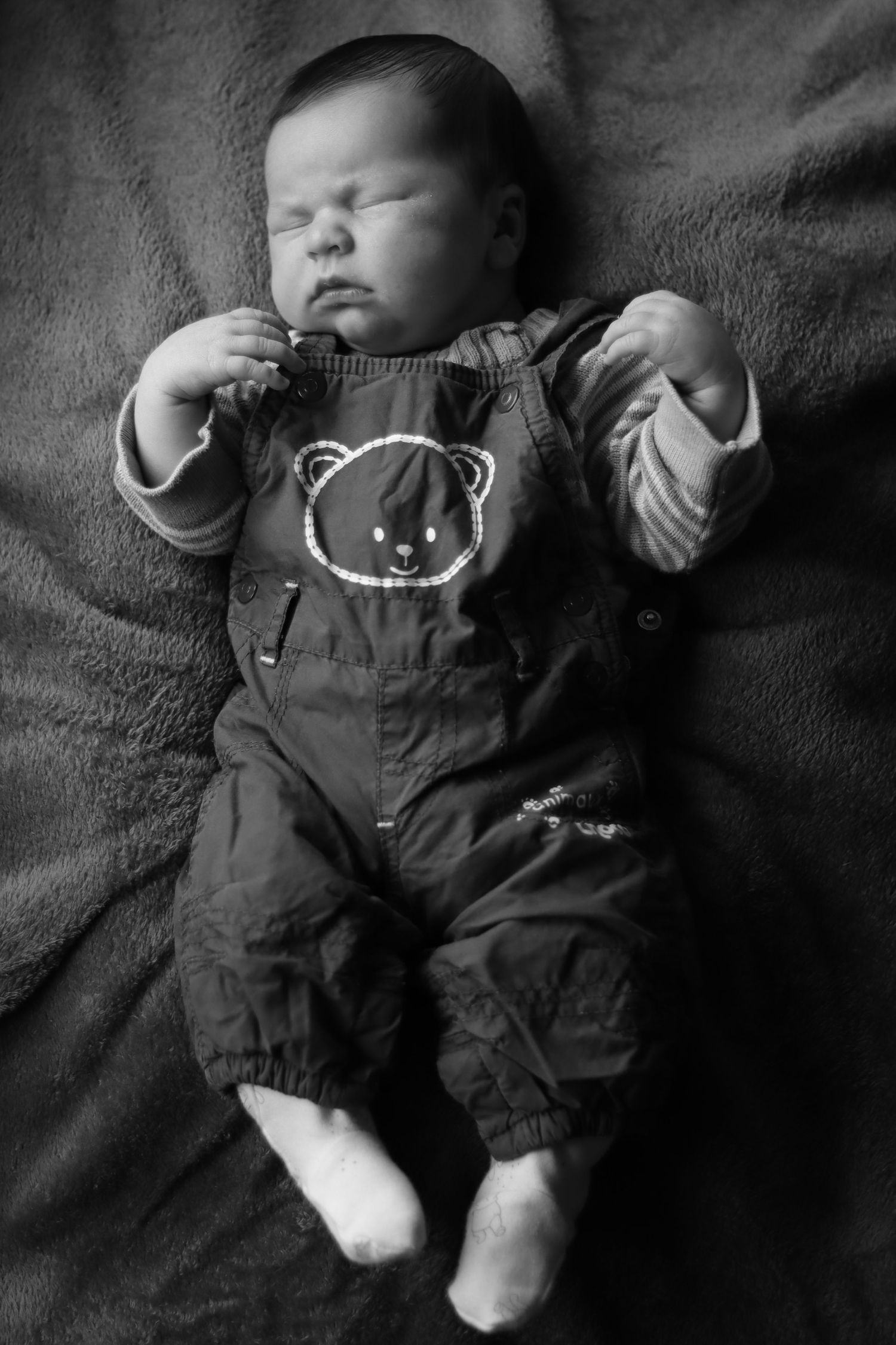 Baby napping in dark outfit on plush charcoal blanket.
