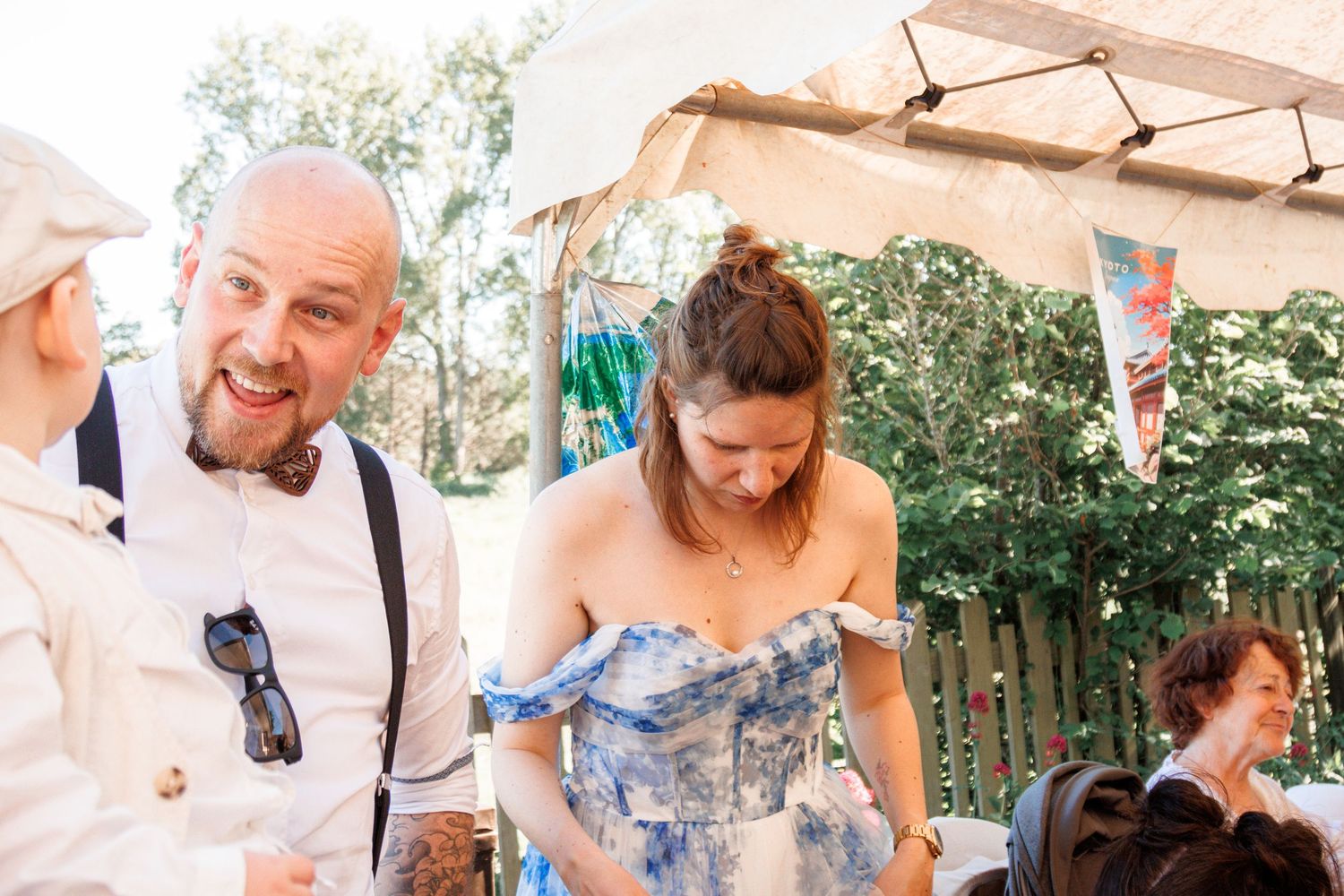 Man in white shirt with suspenders chats with woman in blue floral dress.