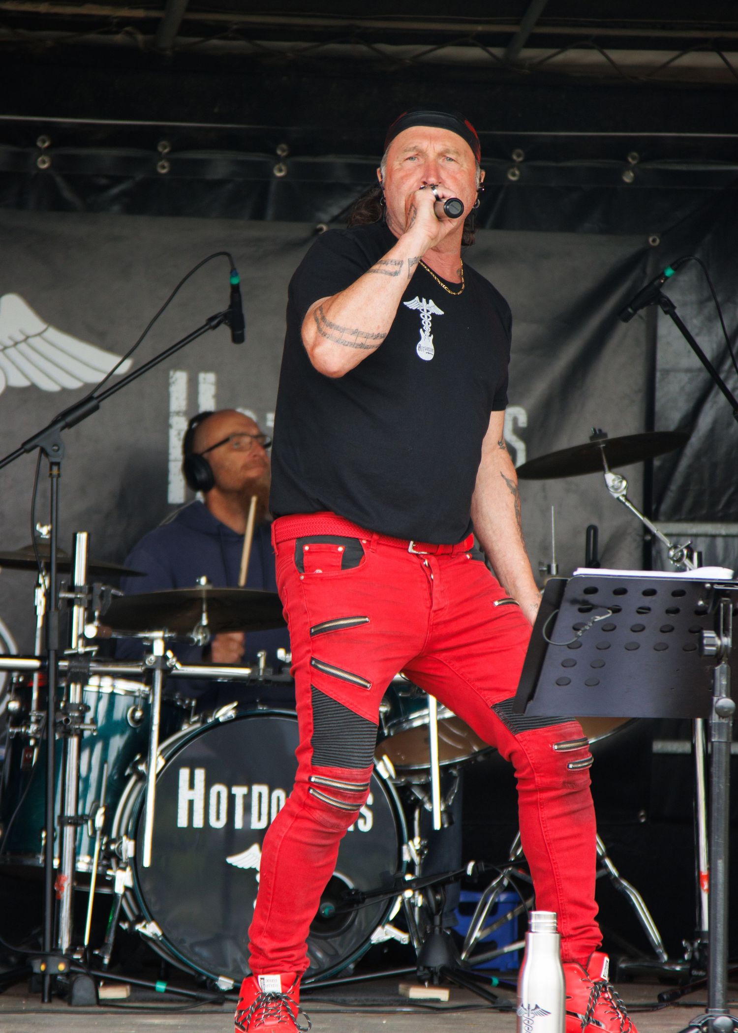 Person performing on stage wearing red pants and black shirt during an energetic show.