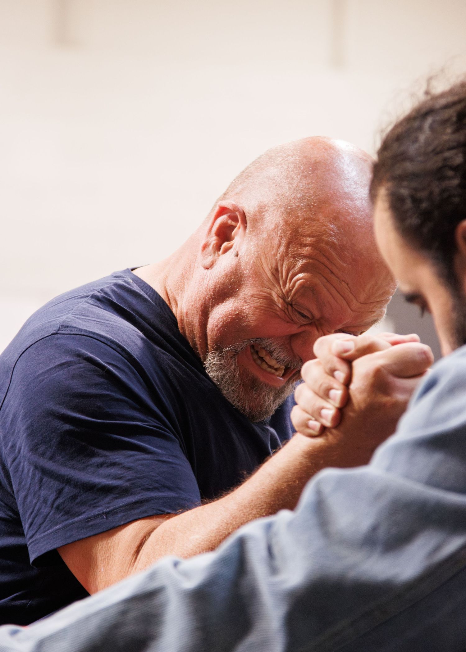 Two competitors locked in intense arm wrestling match wearing casual attire.