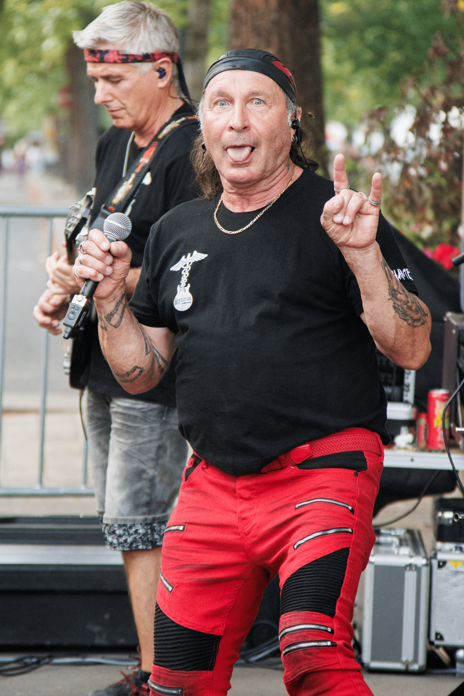 Musicians performing at outdoor concert with red-clad singer and guitarist.