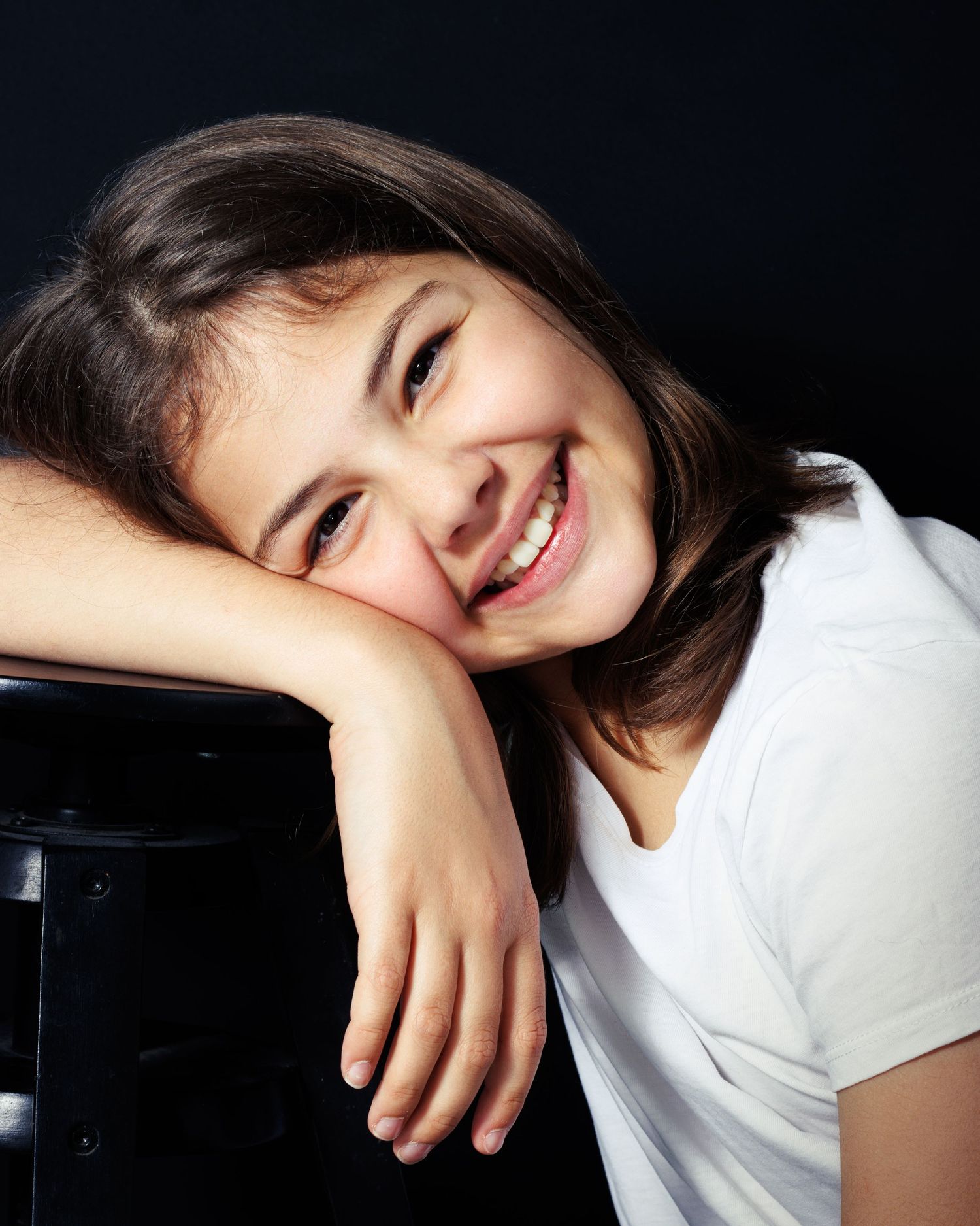 A person in a white t-shirt poses against a dark background in a series of artistic portraits.