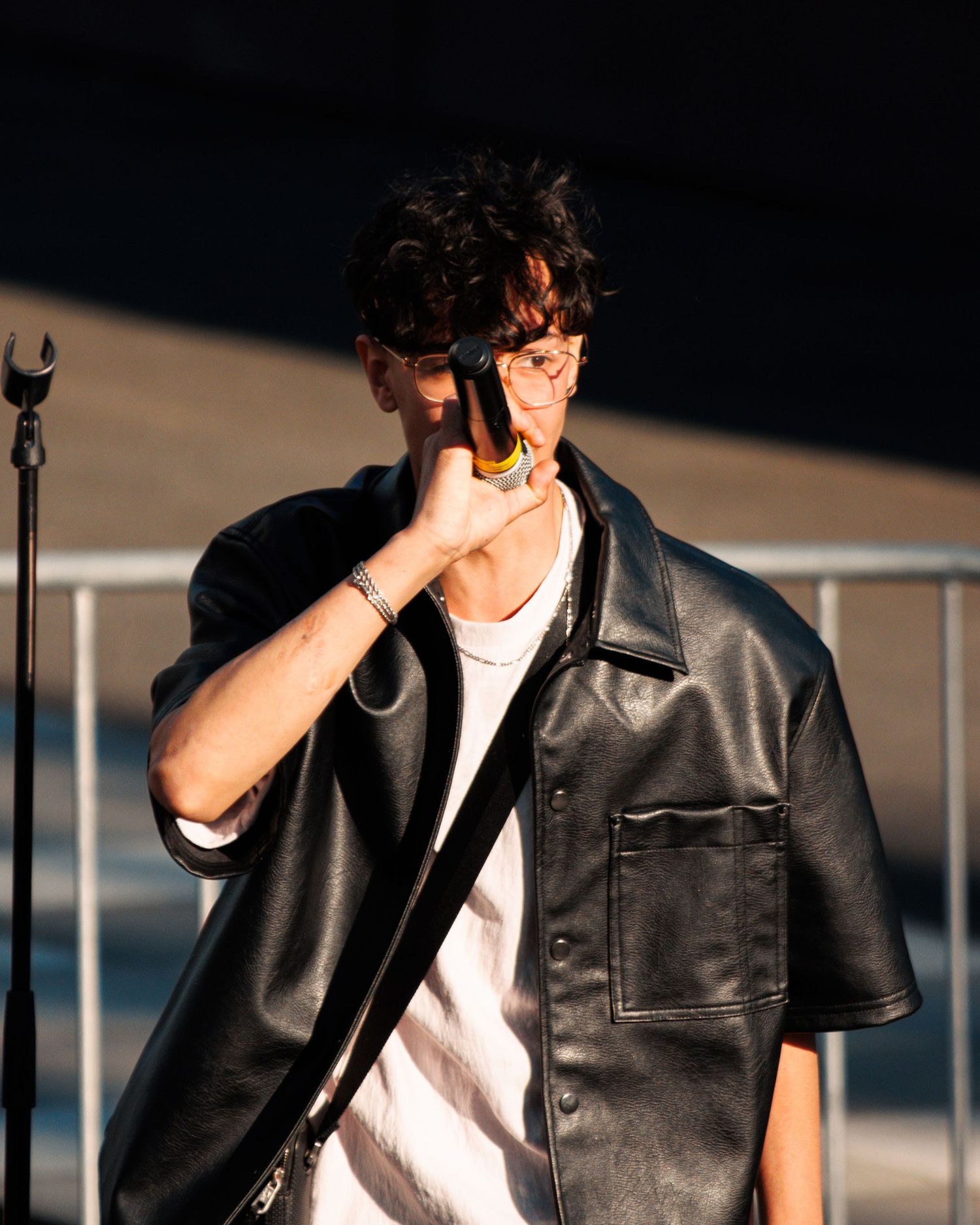 Person in black leather jacket and white shirt performing on stage.