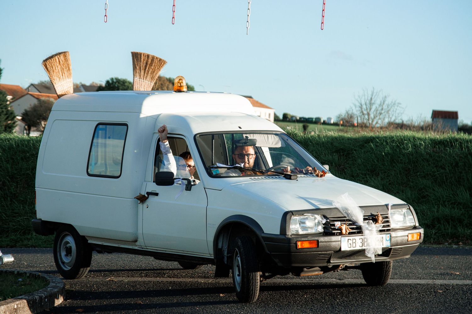 White vintage van with a high roof conversion driving on a road, with a person visible through the window.