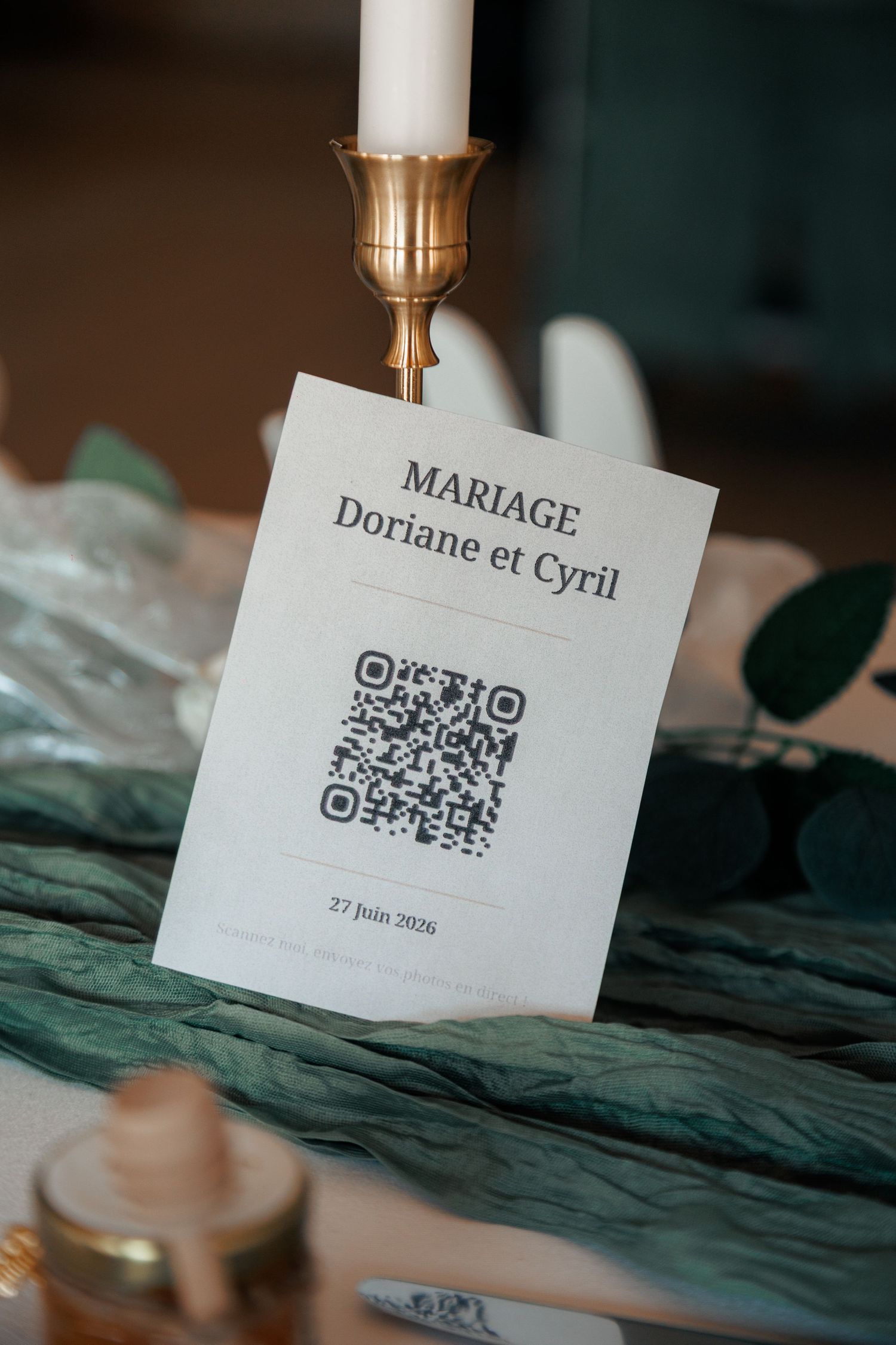 Wedding card for Mariage Doriane et Cyril on 27 June 2026 with QR code, displayed near a gold candlestick.