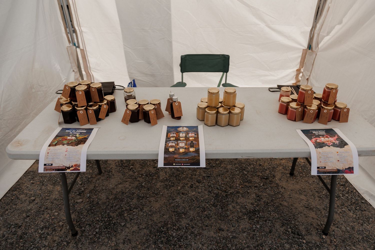Vendor booth displaying handcrafted wooden items and jarred goods on a folding table inside a white tent.