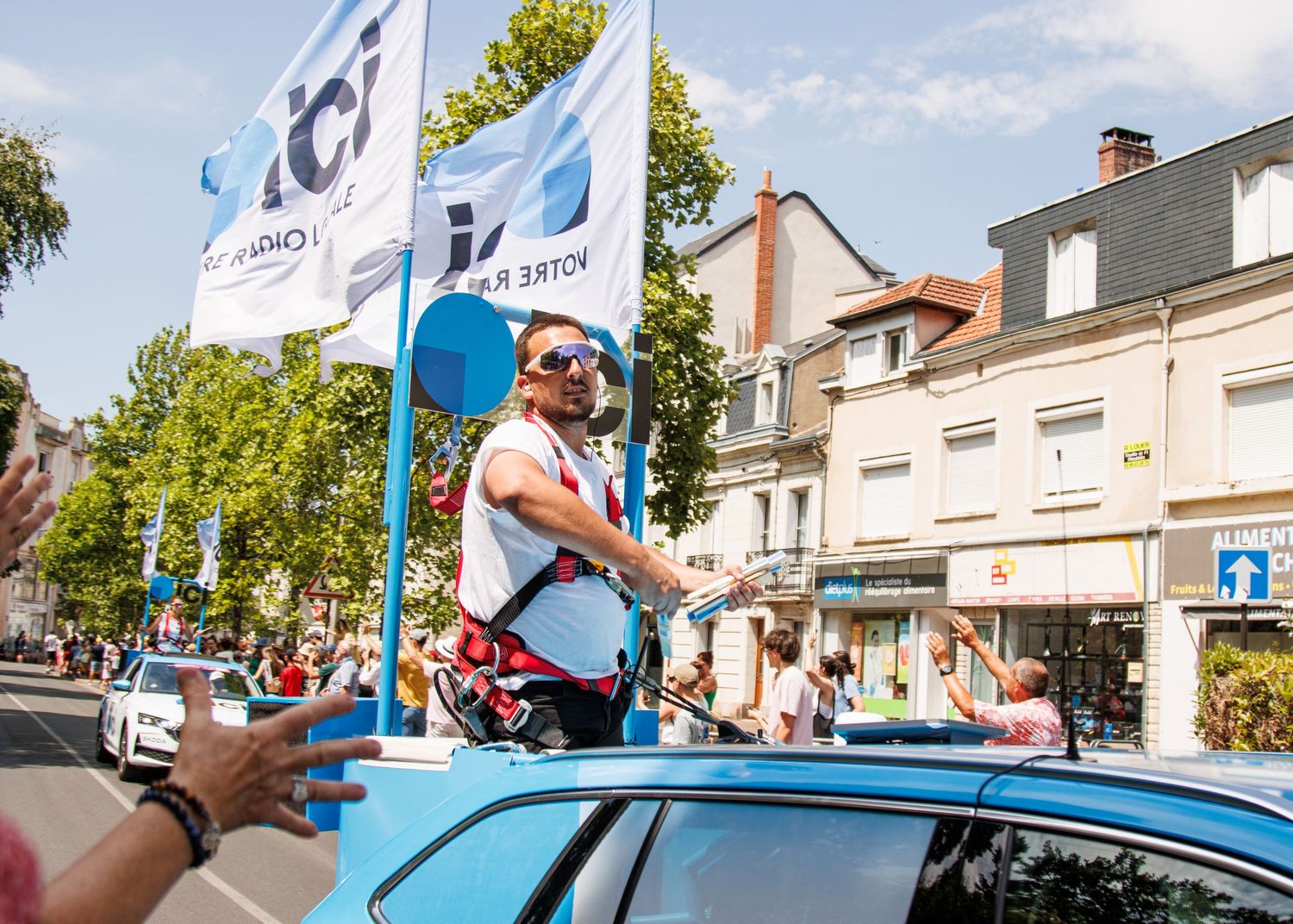 Festival participant on vehicle with blue and white flags during street parade.