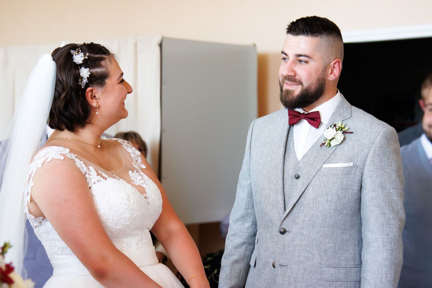 Indoor wedding photography showing couple in formal grey and white attire.