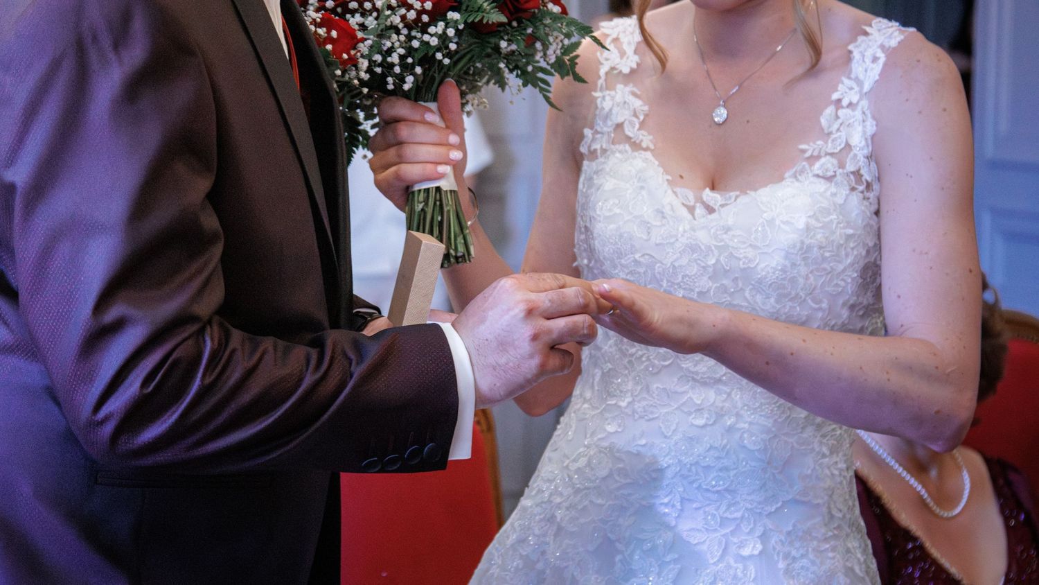 Groom places wedding ring on brides finger during intimate ring exchange ceremony.
