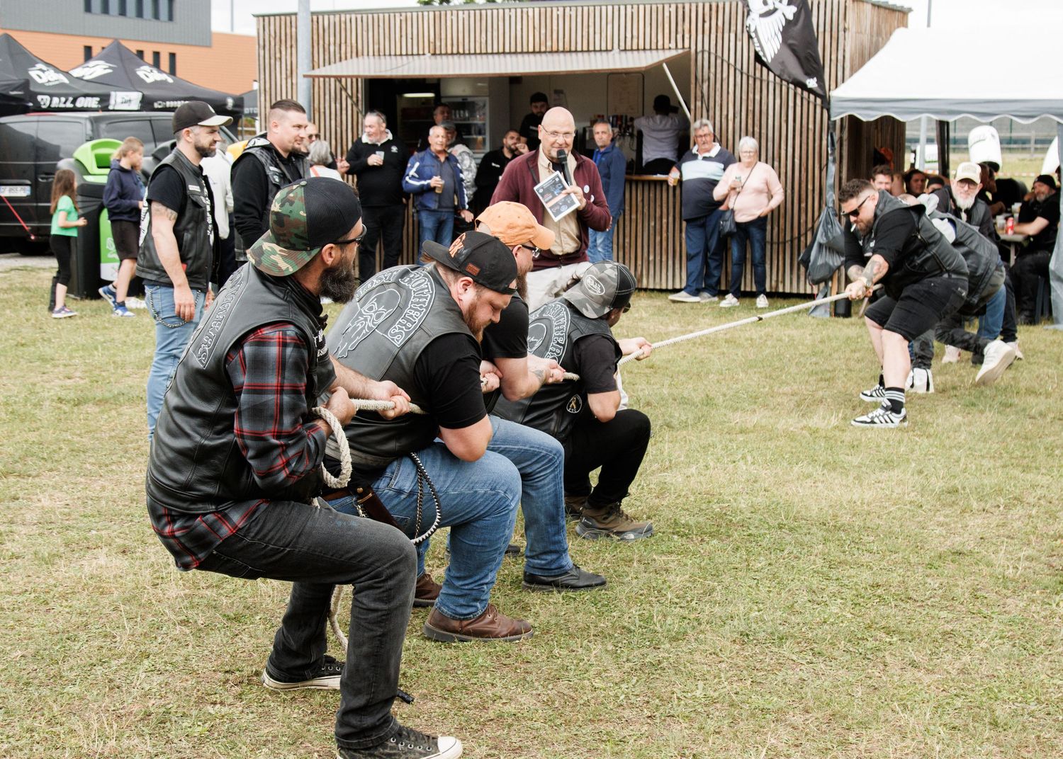 People participating in a group activity on grass near wooden buildings.