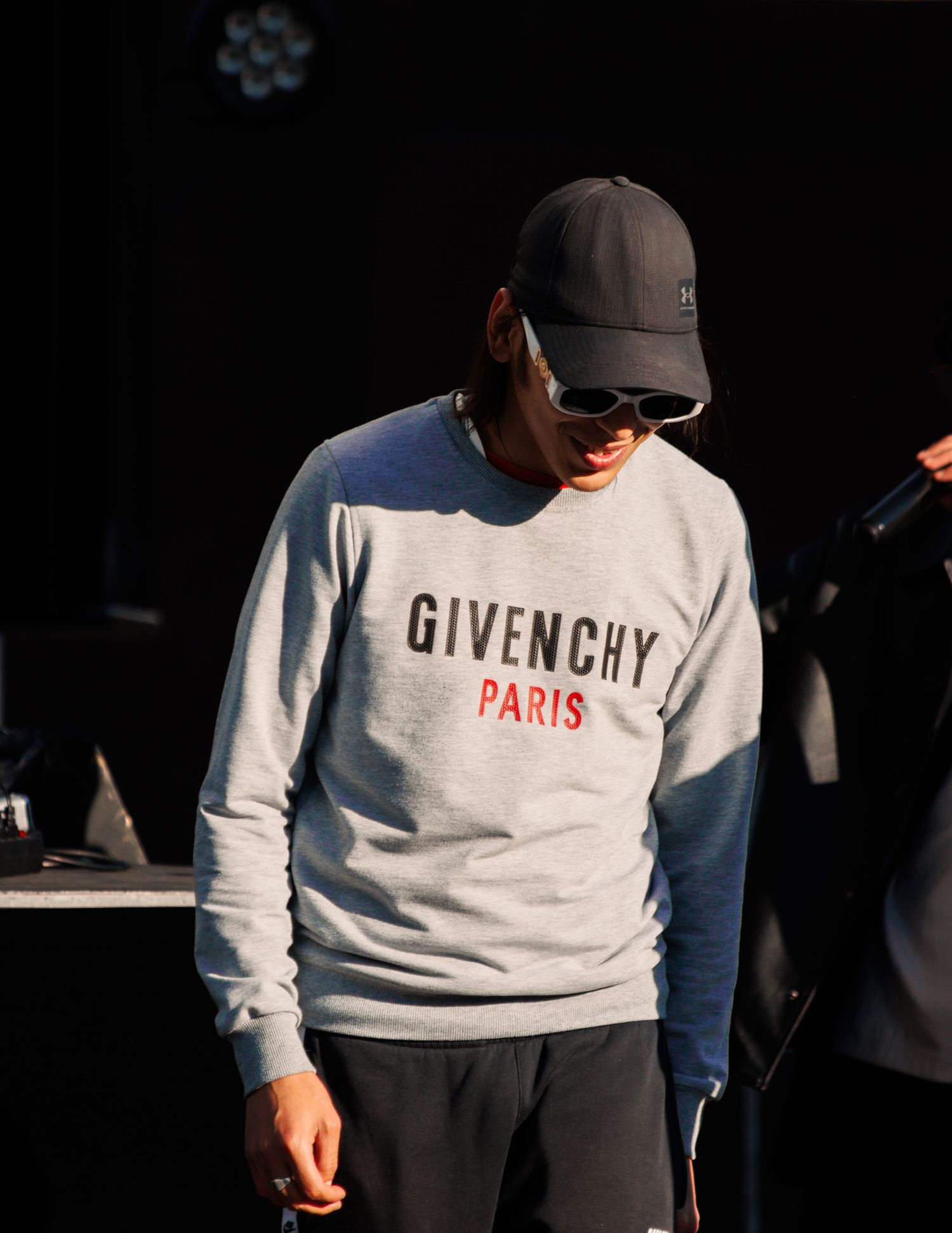 Person wearing white Givenchy Paris sweatshirt in dramatic lighting.