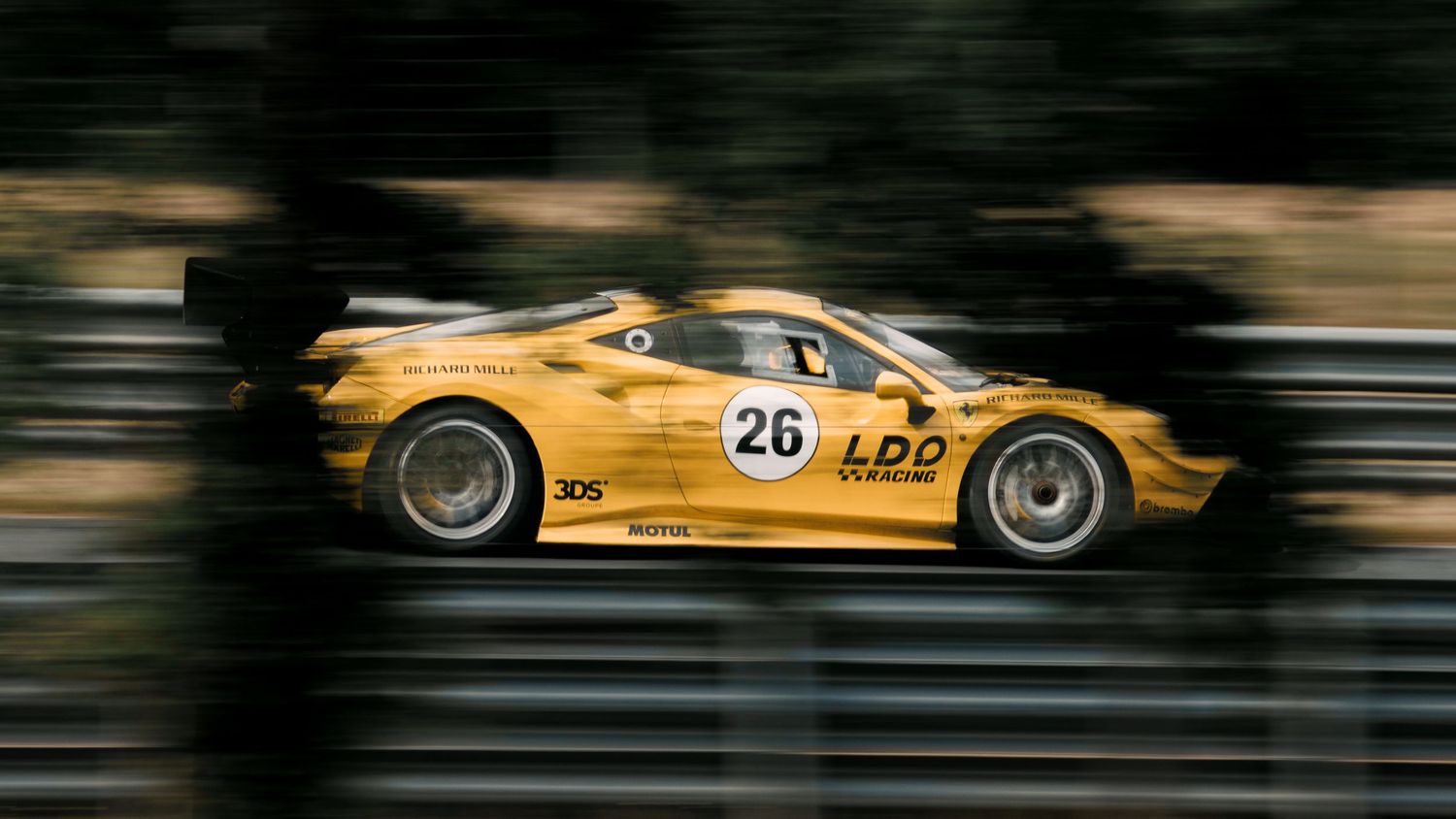 Yellow racing Pagani Zonda with number 26 speeds past with motion blur effect.
