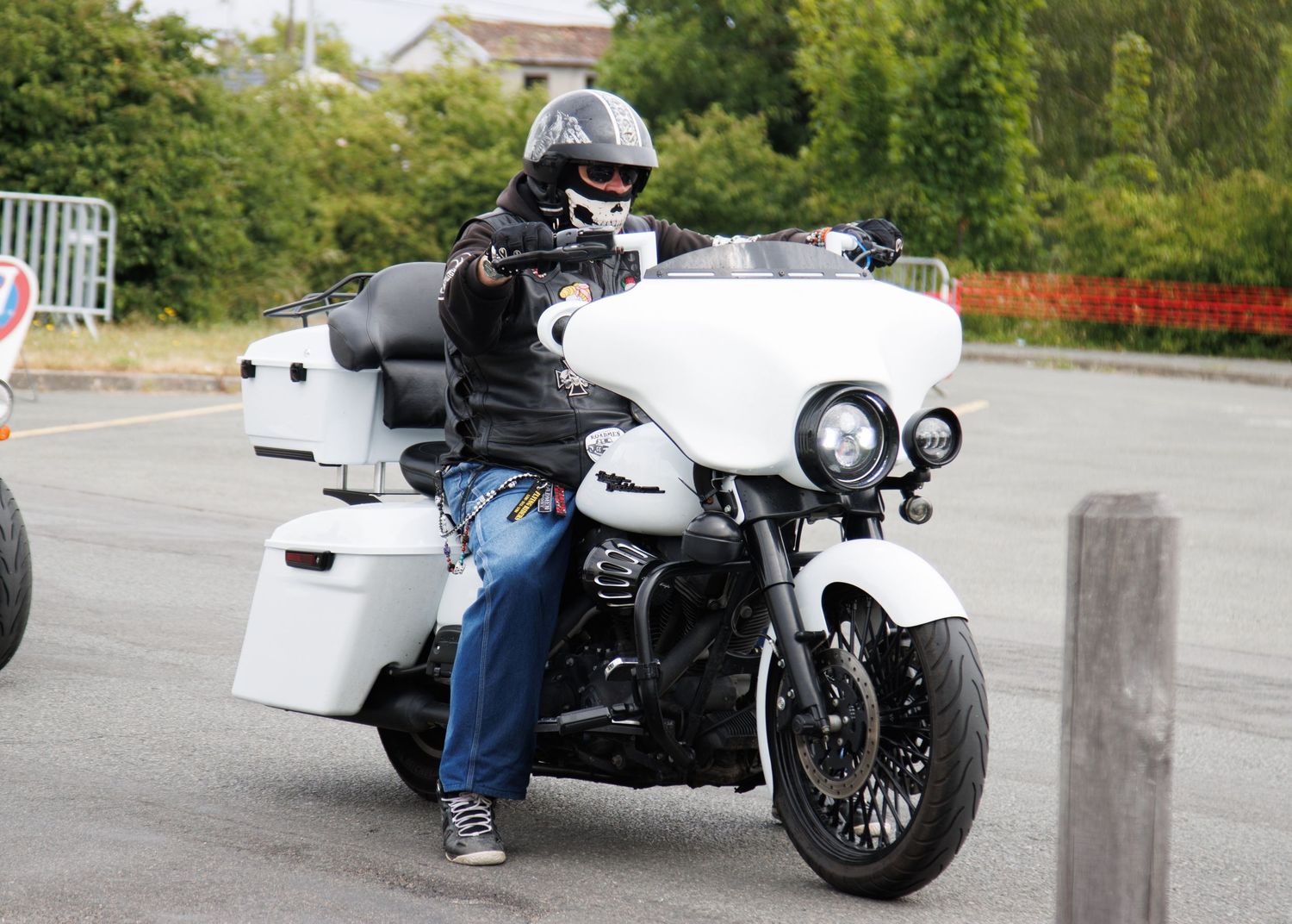A white touring motorcycle being ridden on a suburban street.