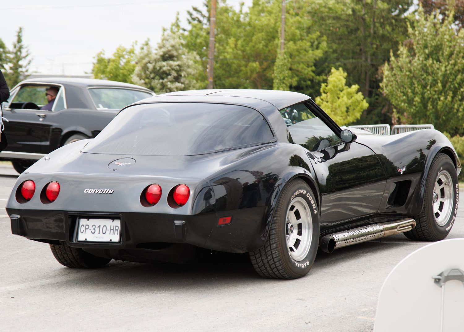 Black Chevrolet Corvette with custom wheels parked in a lot.