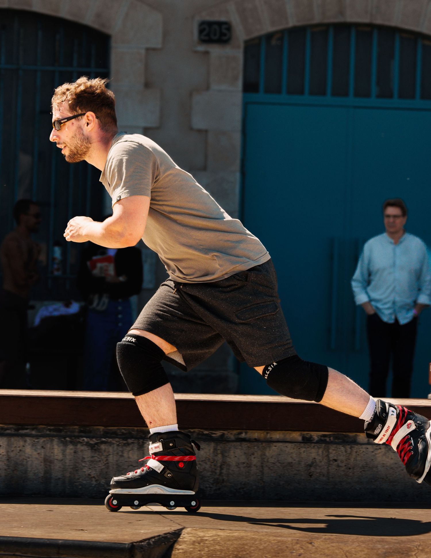 Skater performs sliding trick across wooden ramp in afternoon sunlight.