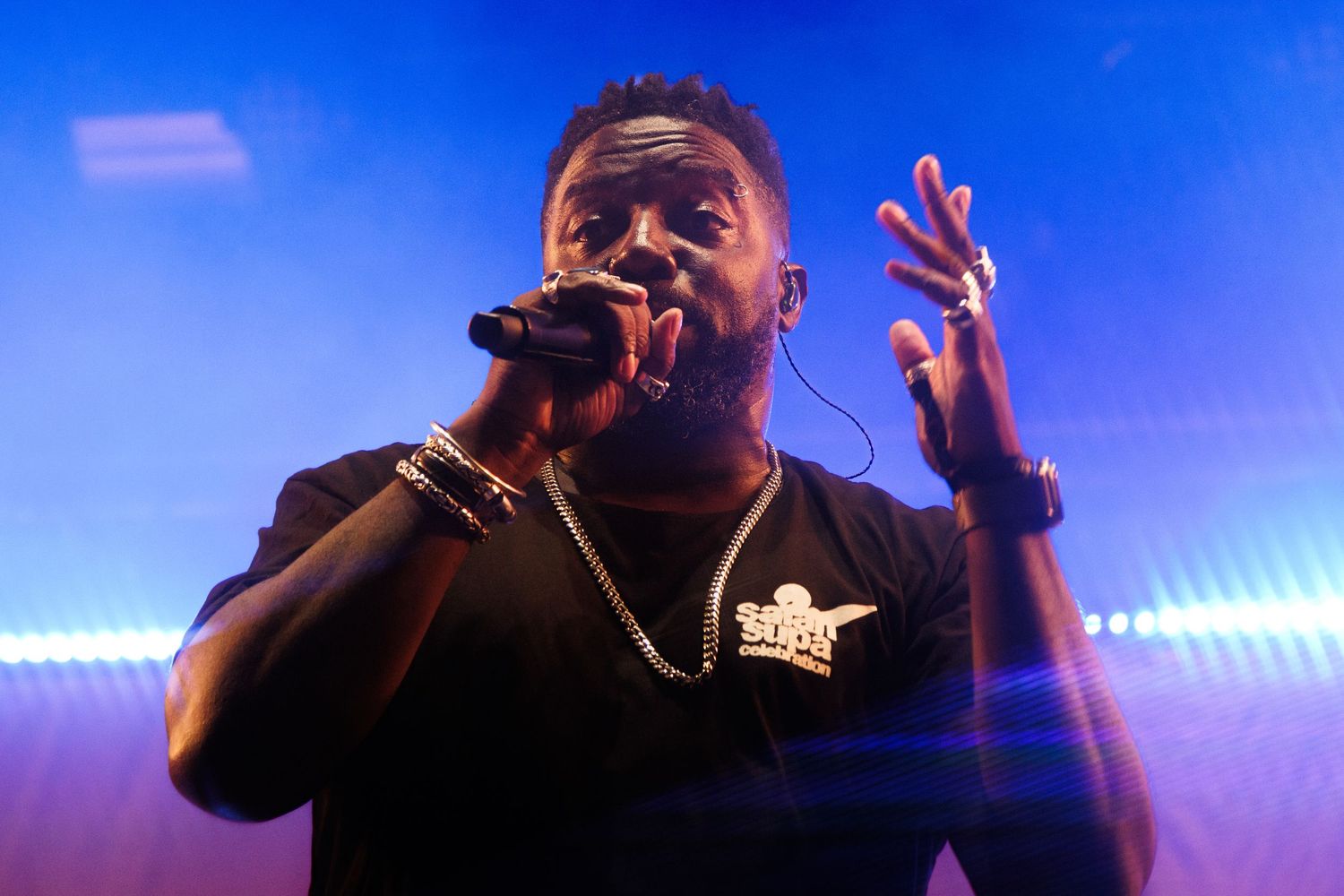 A performer on stage silhouetted against blue concert lighting during an energetic musical performance.