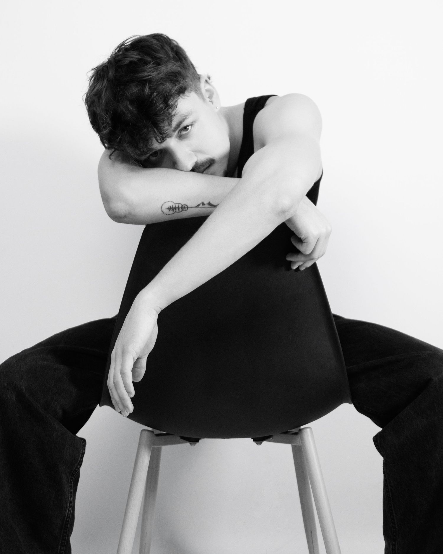 A series of black and white photos showing a person in dark clothing resting on a white chair in various contemplative poses.