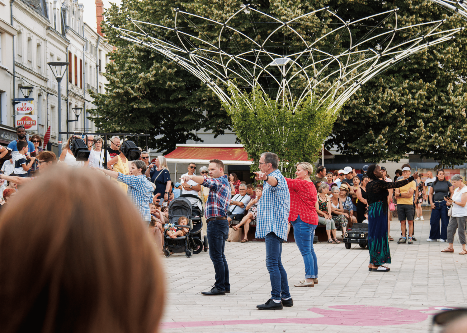 Crowd gathering at an outdoor event space with performance equipment visible.