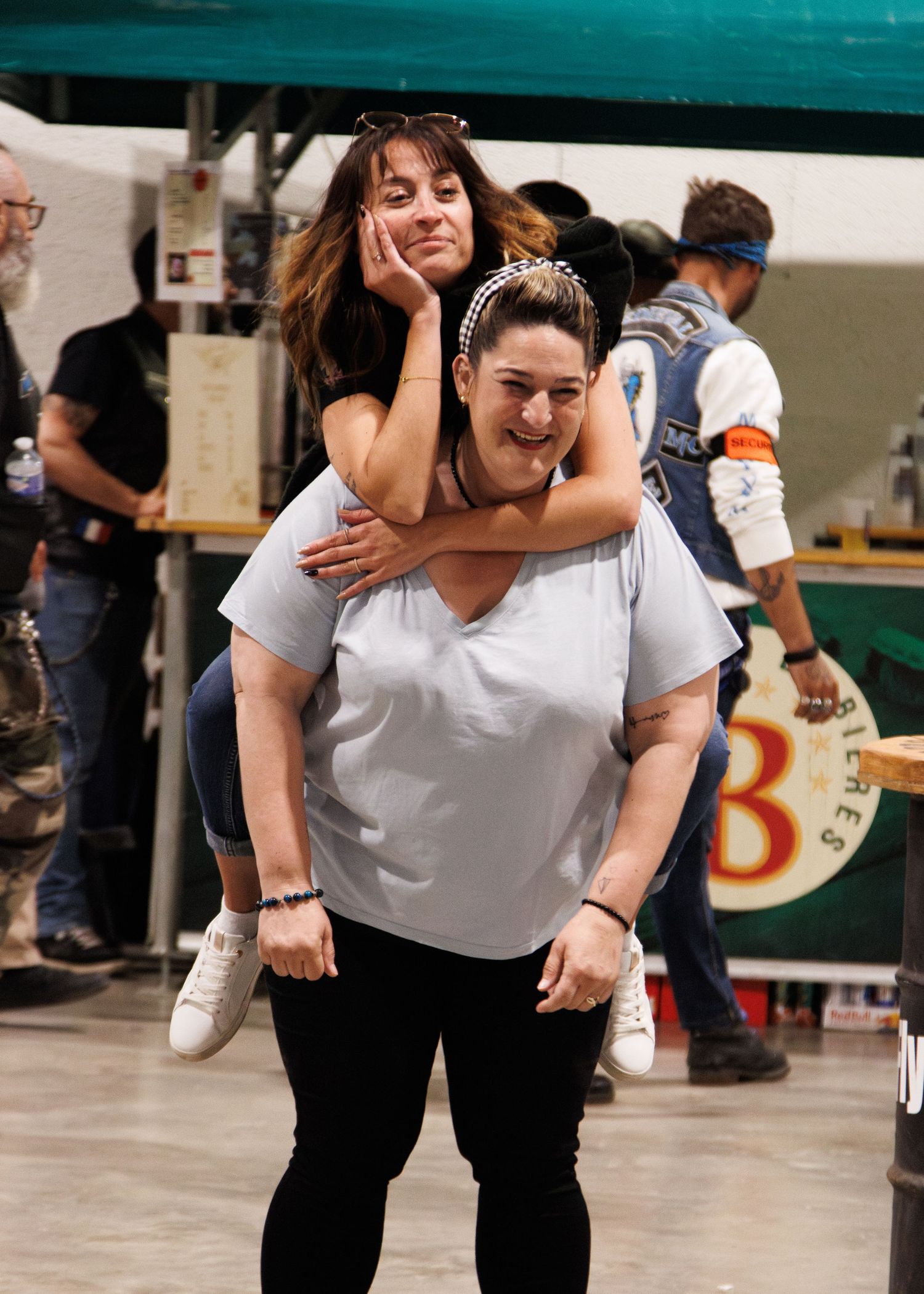 A playful piggyback ride moment captured during what appears to be an indoor event.