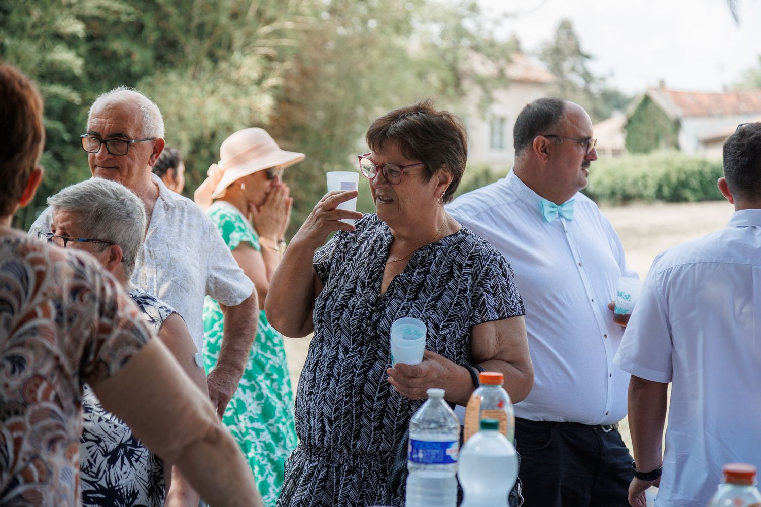 Elegantly dressed wedding guests socializing outdoors while enjoying drinks at a reception.