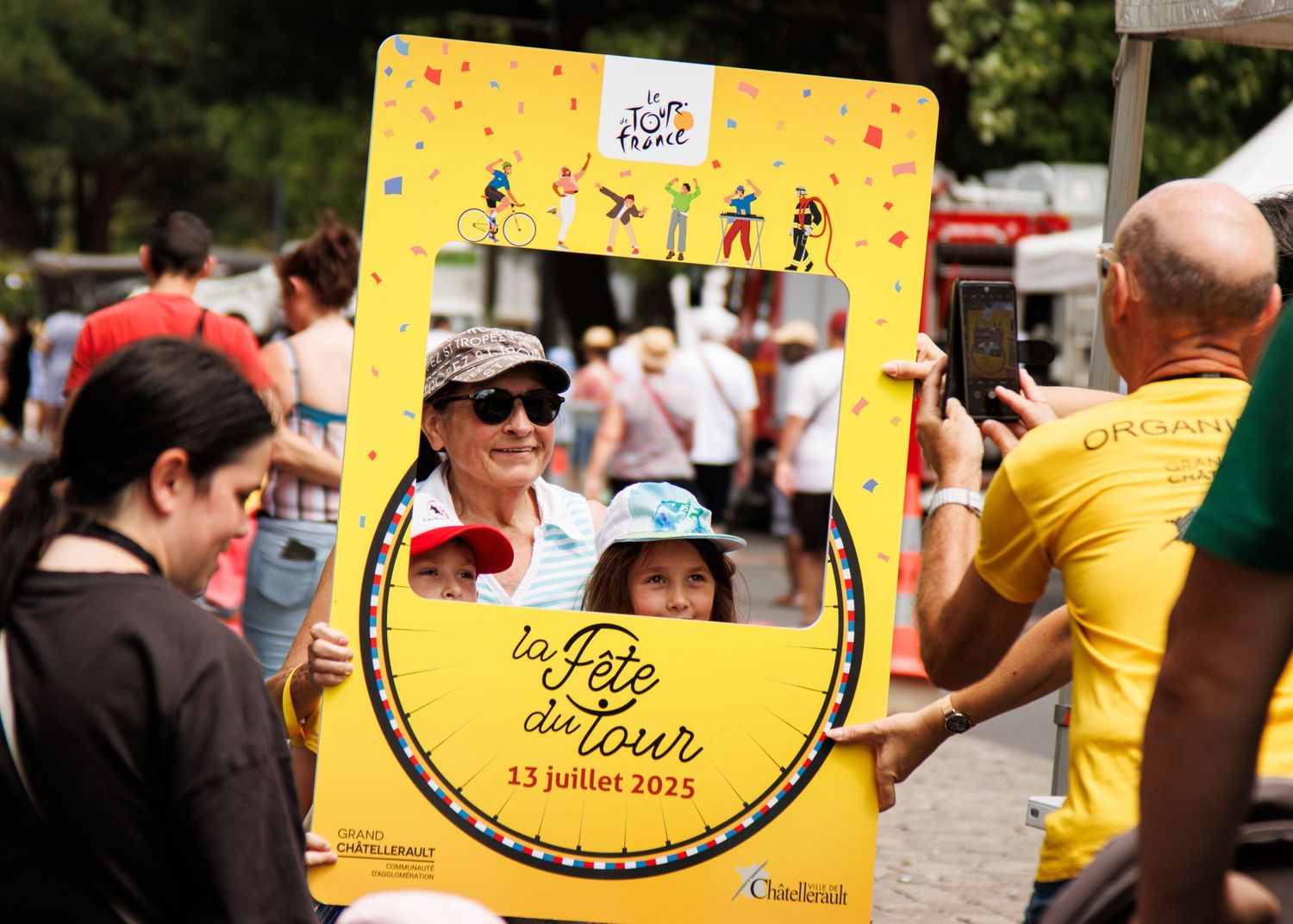 Yellow promotional banners and decorations line a crowded outdoor event space.