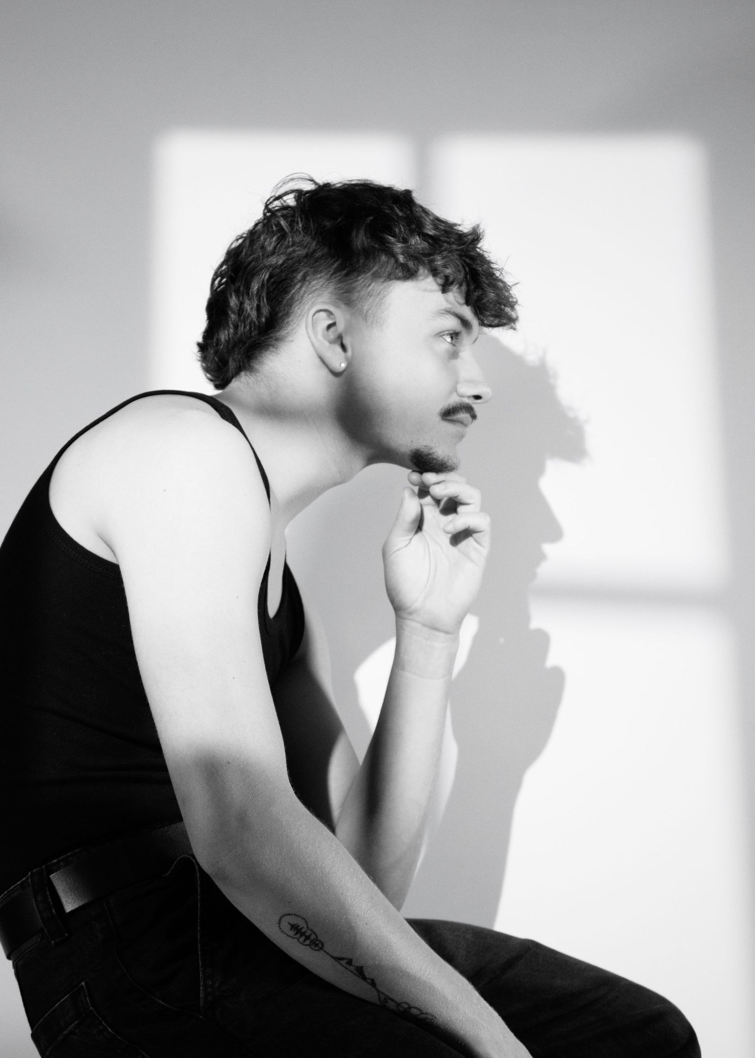 A black and white photo sequence showing a person in a dark top leaning back with dramatic shadow play on the wall.