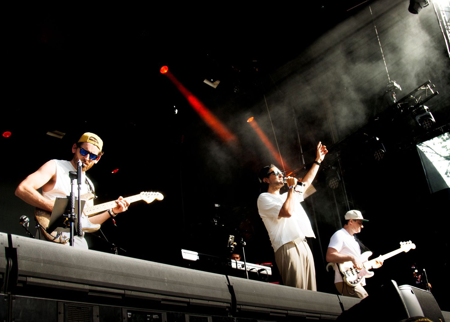 Energetic live music performance with dramatic stage lighting showing musicians playing instruments on a dark stage.
