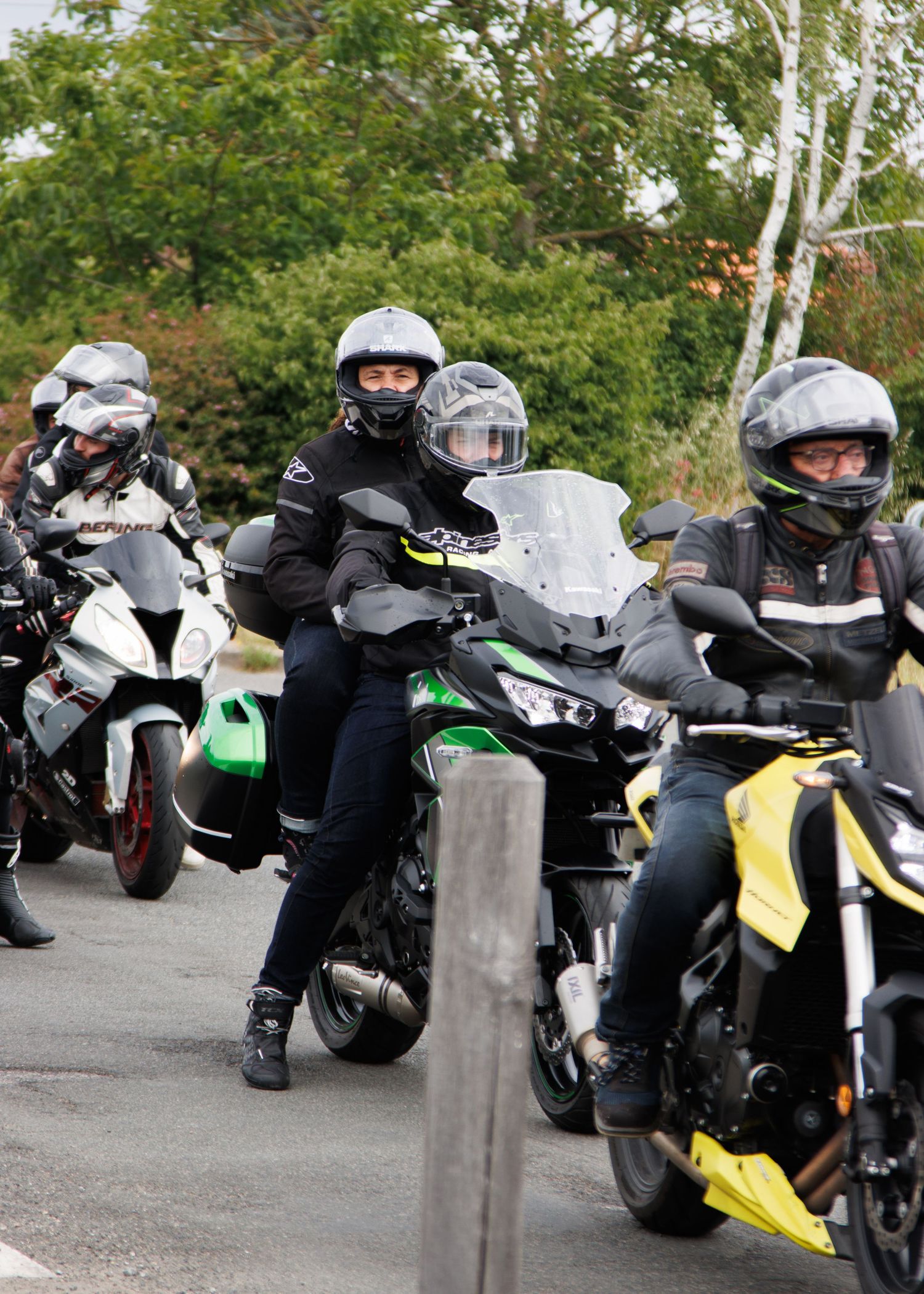 Group of motorcyclists in protective gear riding sport bikes on a curved road.