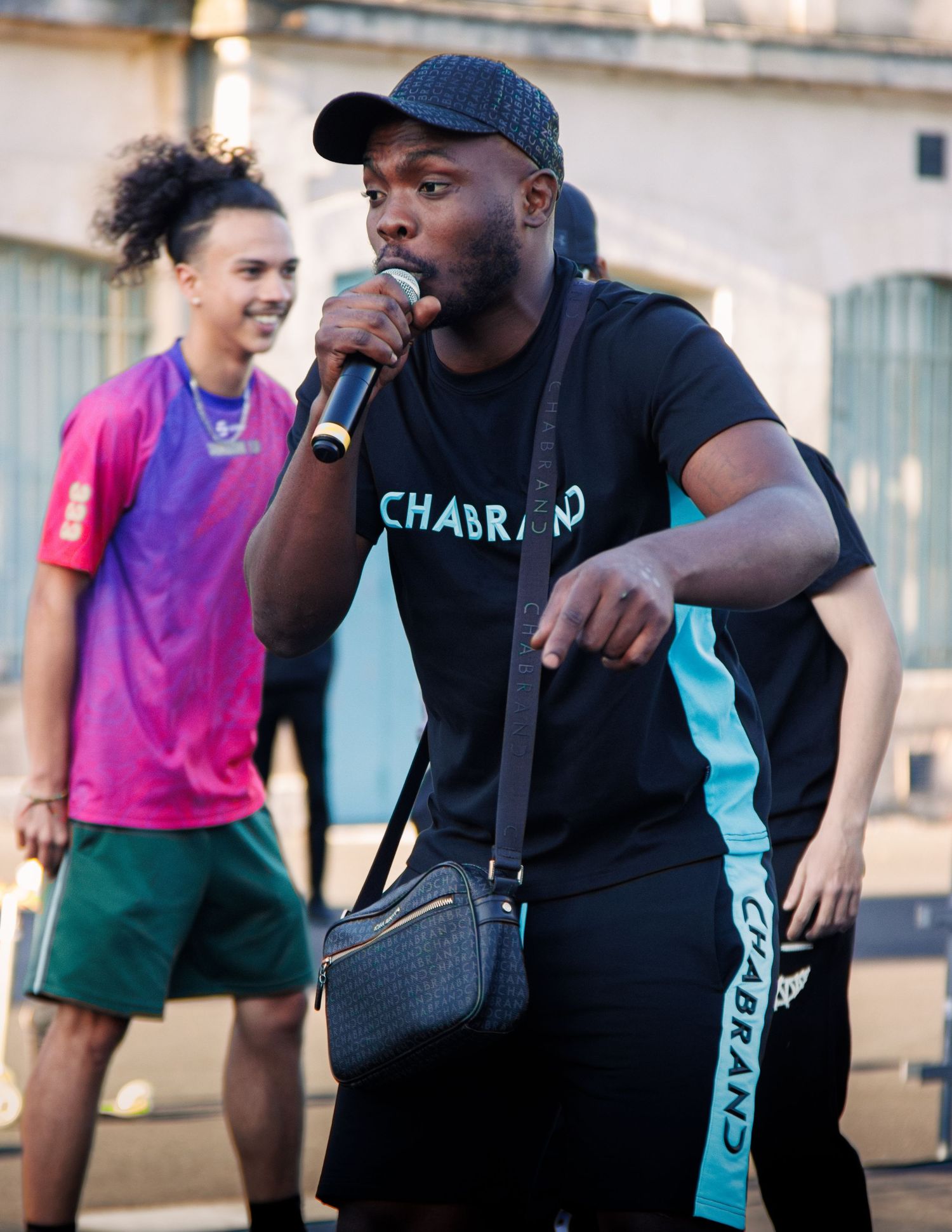 People performing at outdoor event with microphone and casual attire.